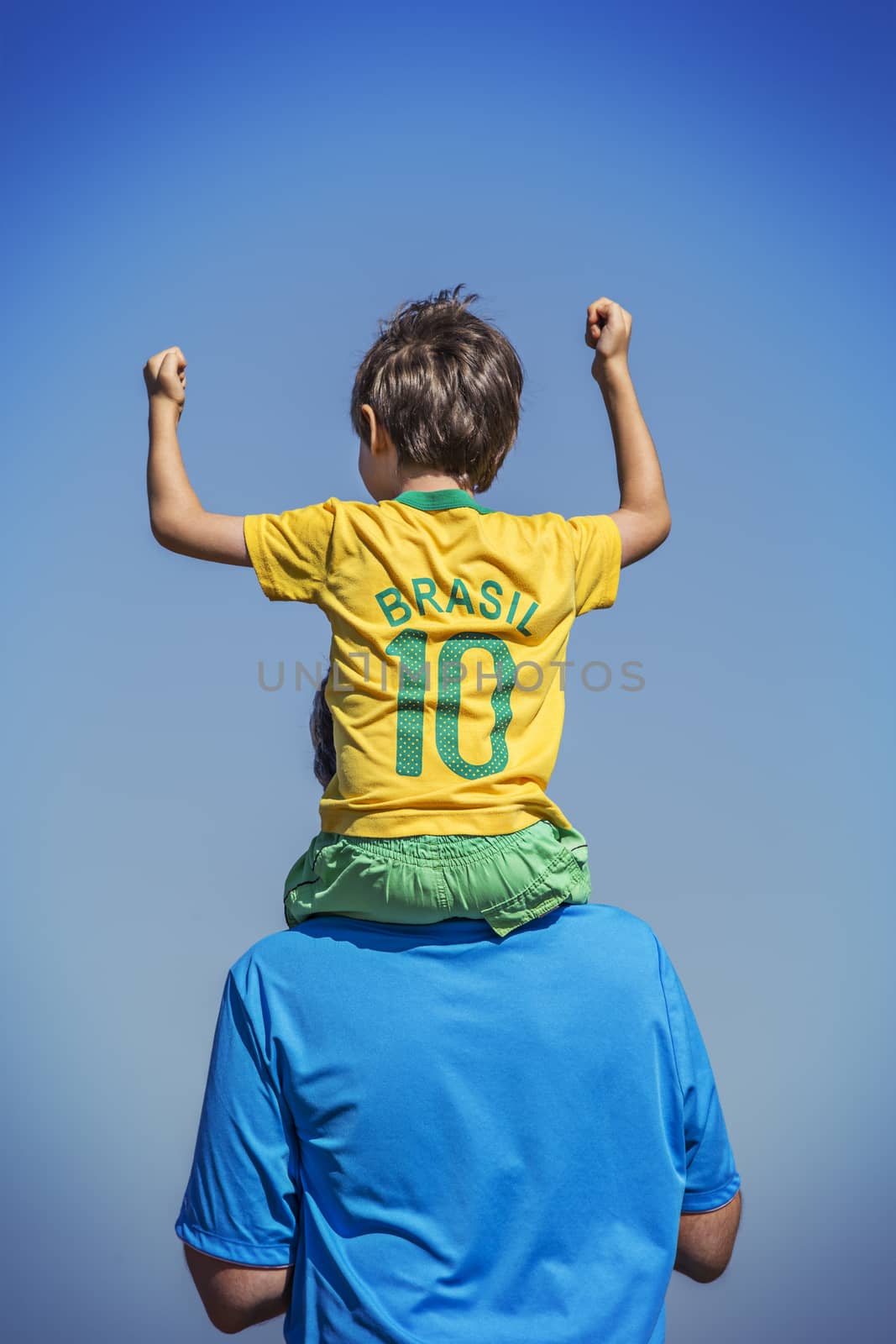 Father with cheering son sitting on his neck. Blue sky. by BrazilPhoto