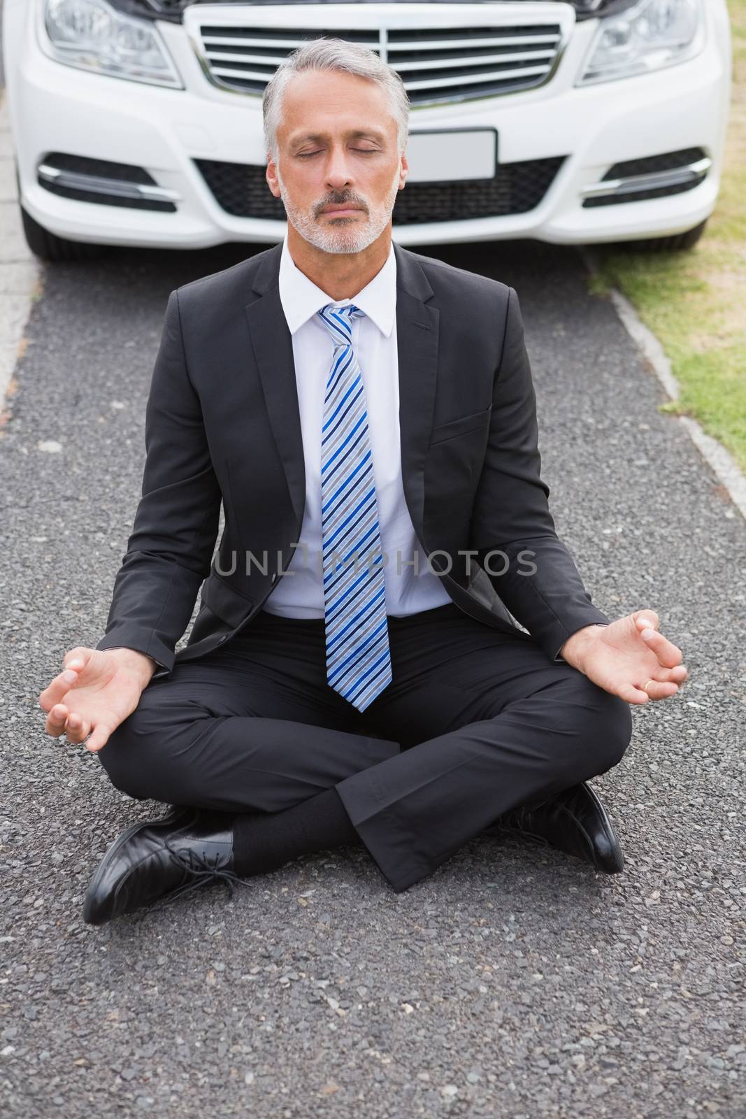 Businessman meditating after his car broken down on the road 