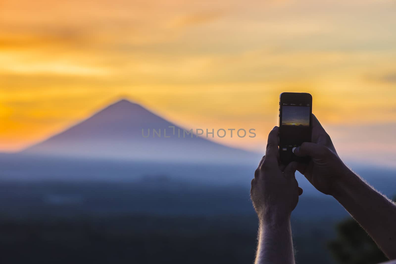 Man with Mobile Phone and Volcano Agung as Background. by truphoto
