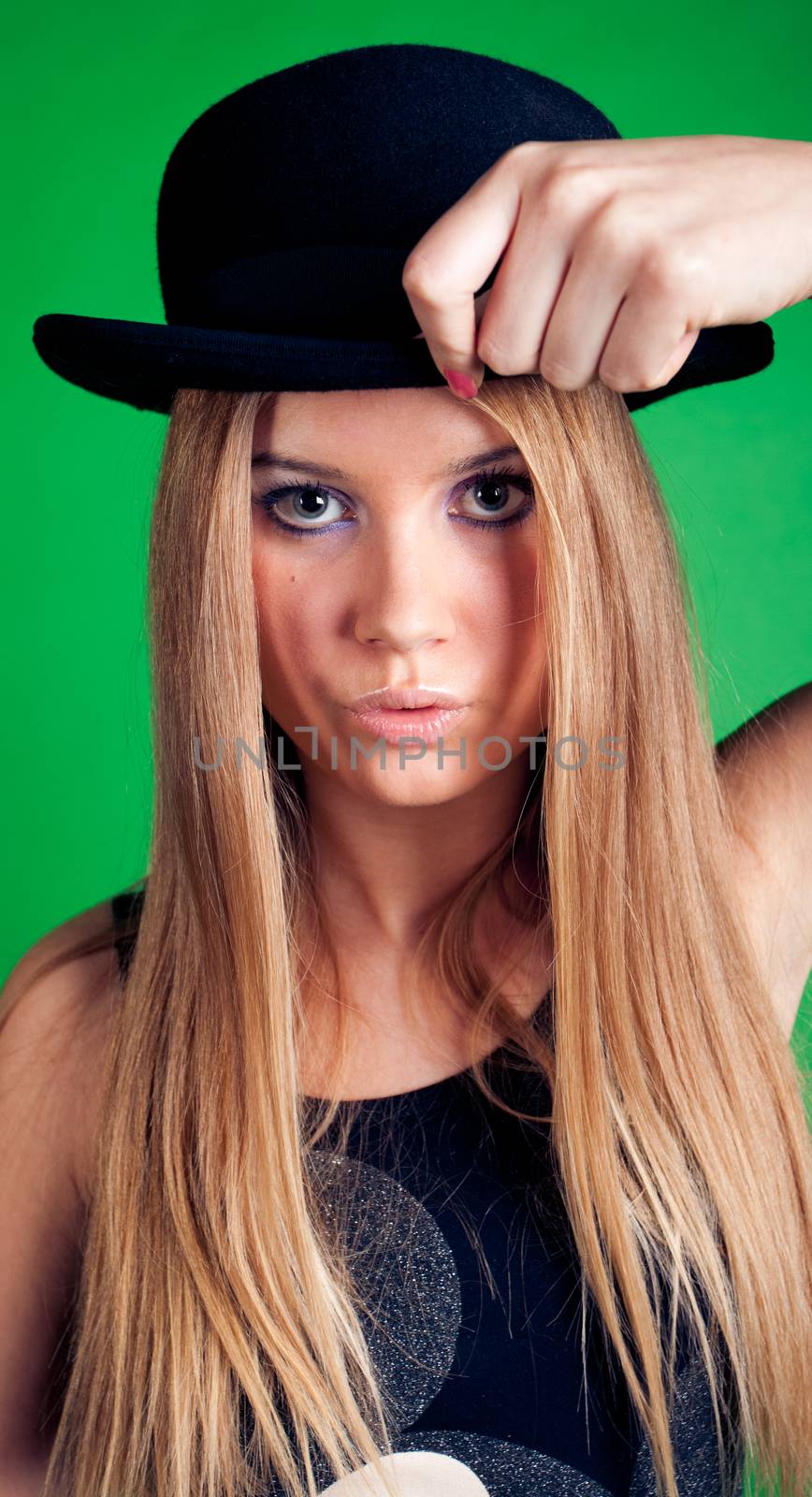 Young women with hat in hand on green background