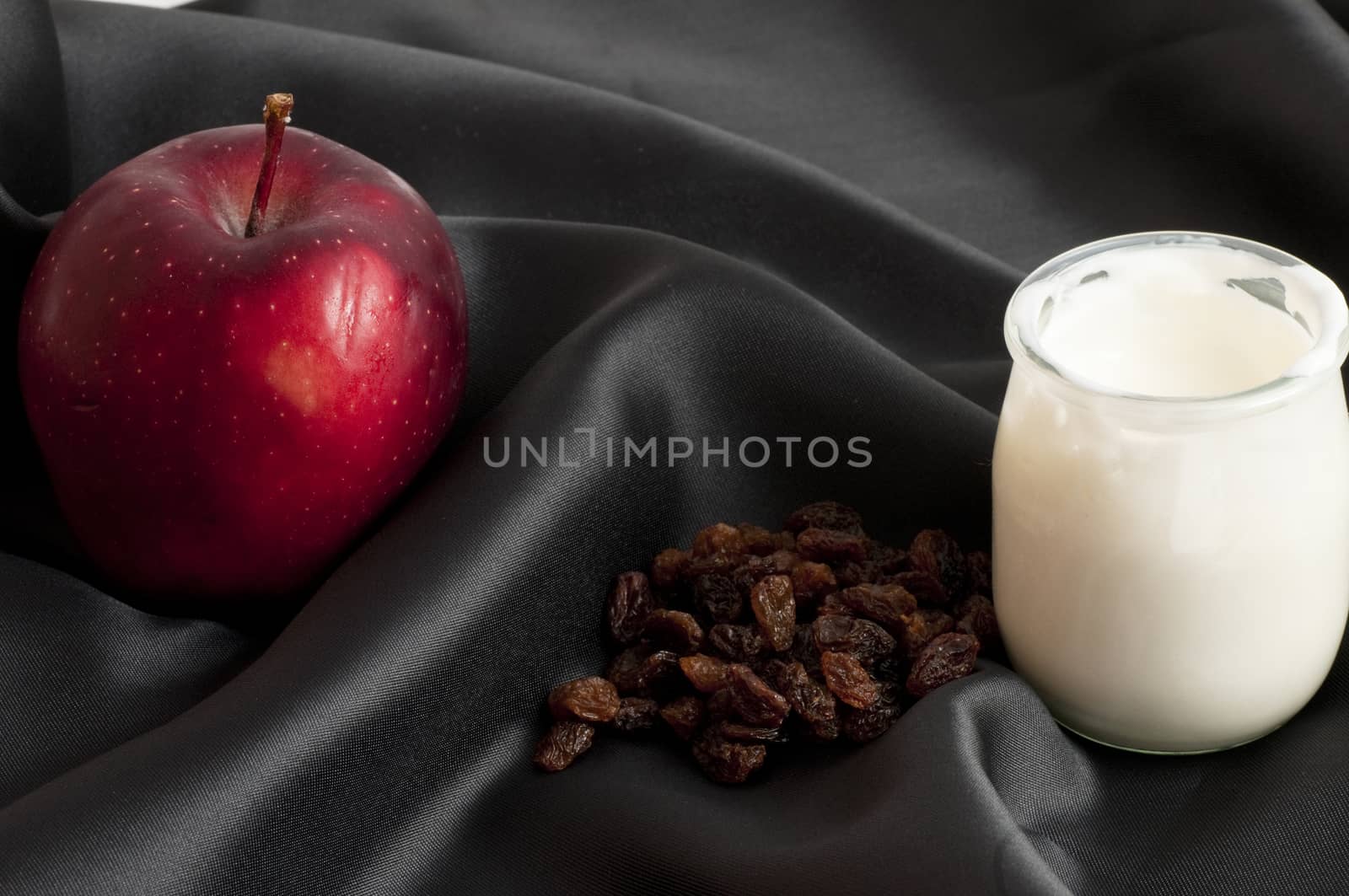 white yoghurt in a bowl on a sheet of black silk with close blueberries and apple