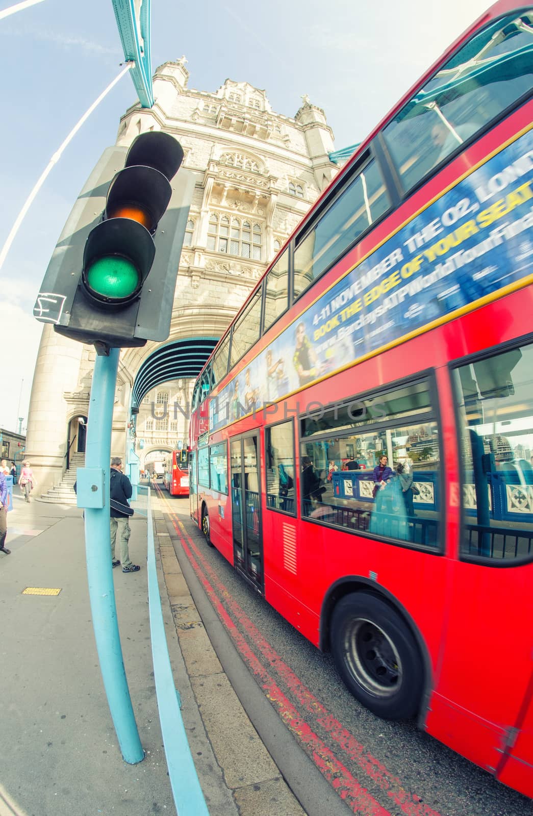 LONDON - SEPTEMBER 28, 2013: Bus crossing Tower Bridge with tourists walking. The city is visited by more than 40 million people annually.