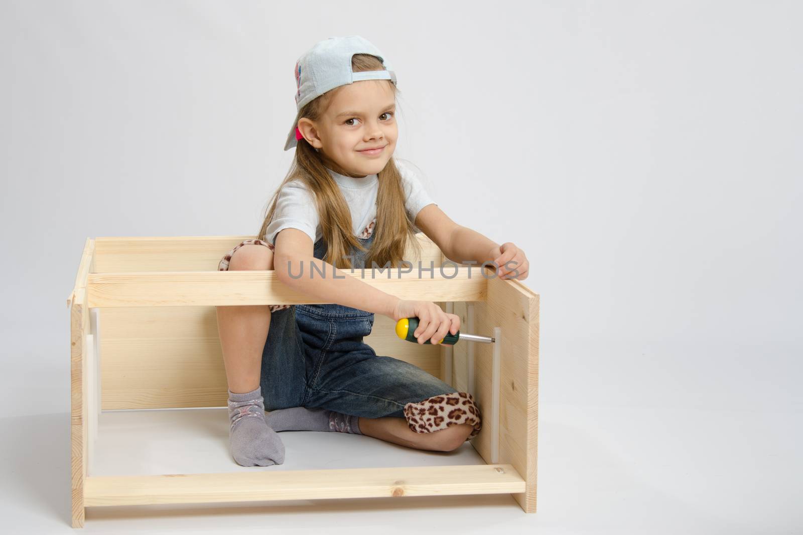 Six year old girl playing and collecting wooden cabinet