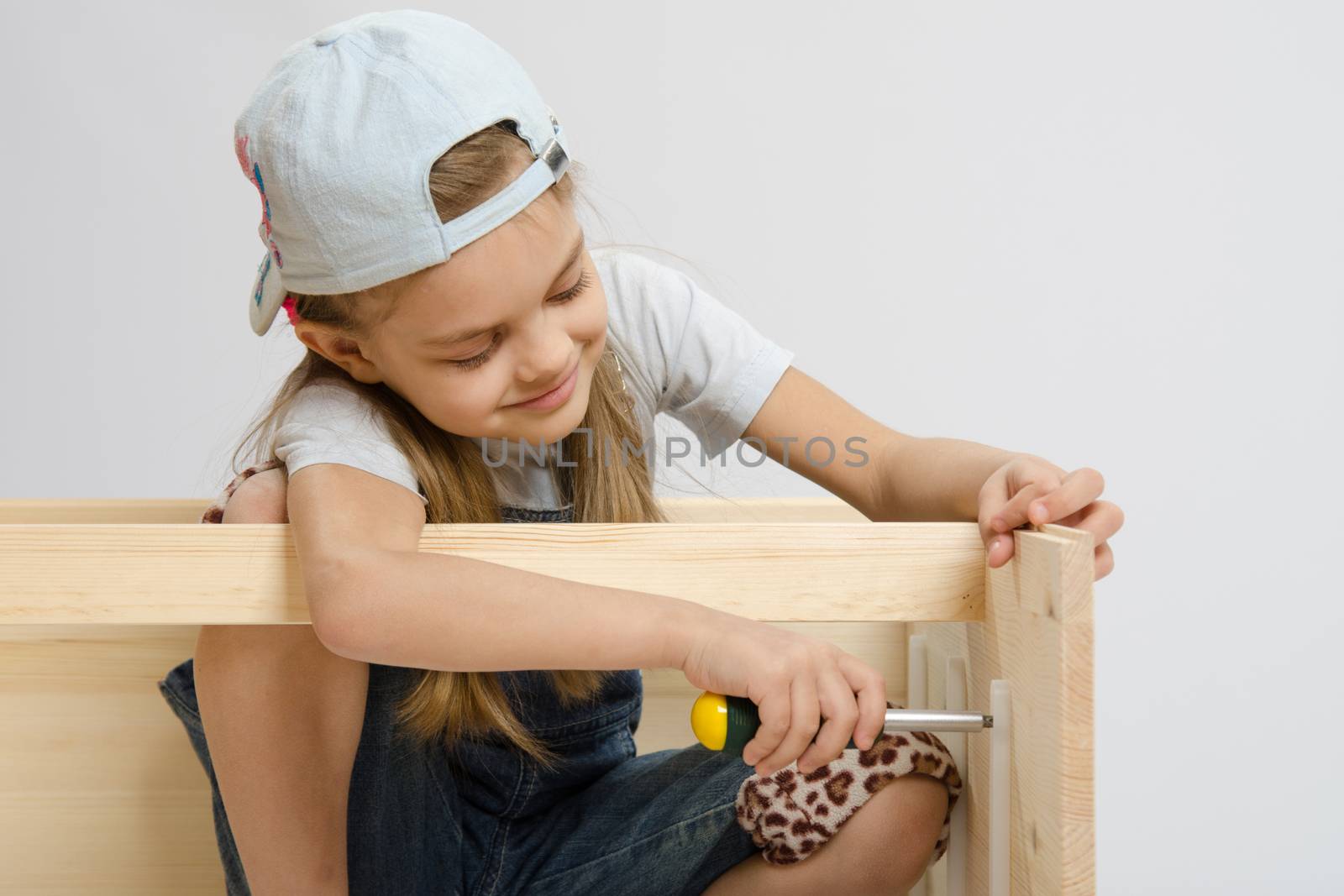 Six year old girl playing and collecting wooden cabinet