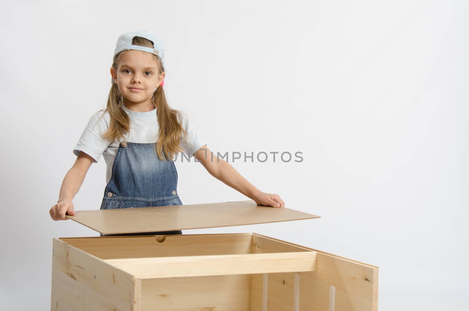 Six year old girl playing and collecting wooden cabinet