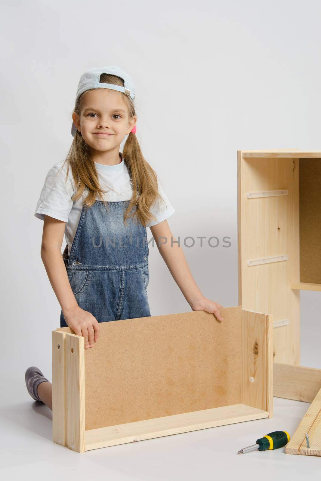 Six year old girl playing and collecting wooden cabinet