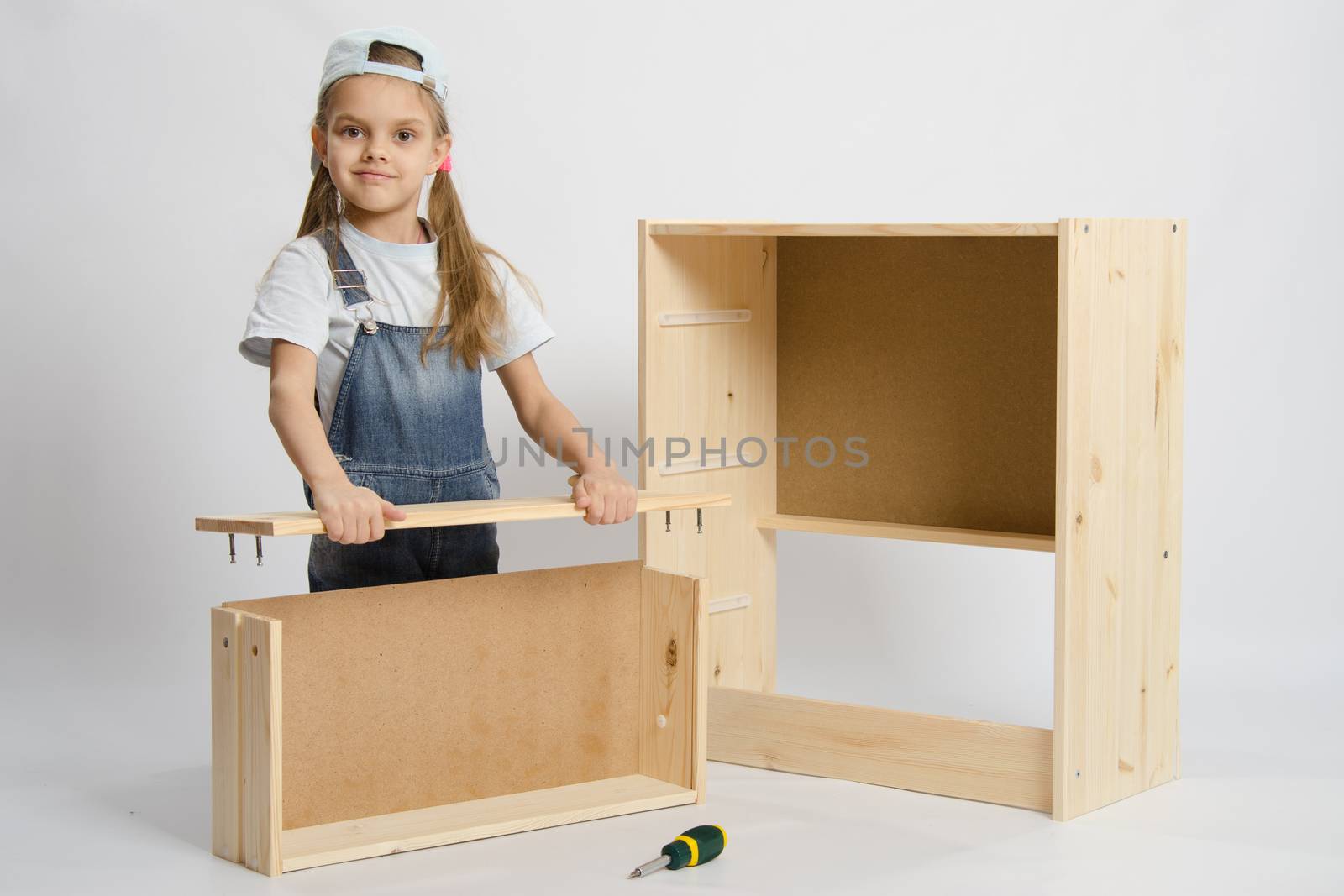 Six year old girl playing and collecting wooden cabinet