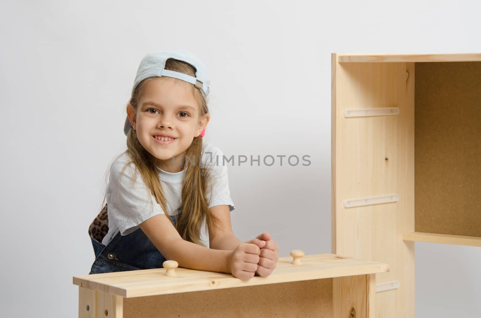 Six year old girl playing and collecting wooden cabinet