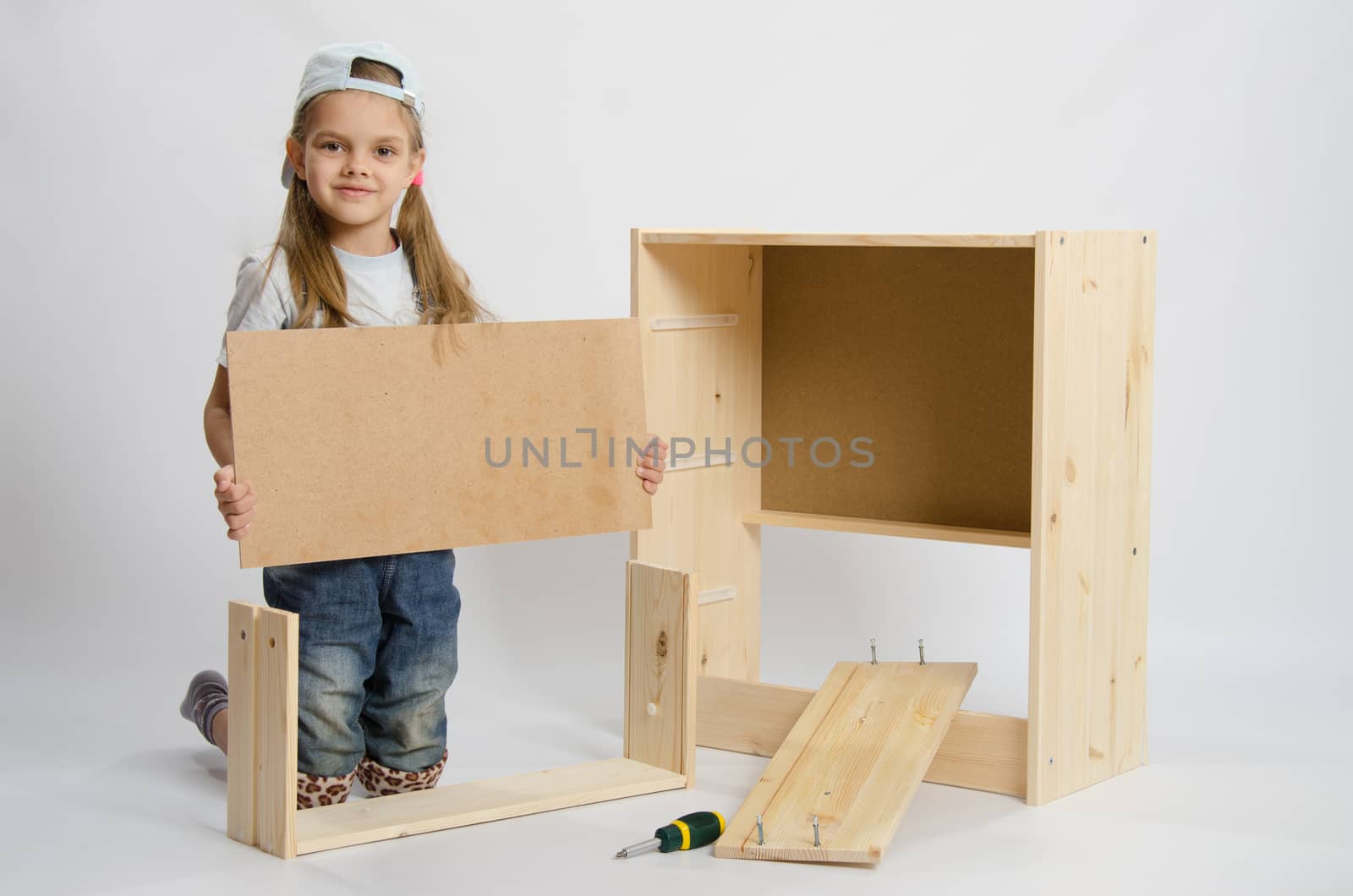Six year old girl playing and collecting wooden cabinet