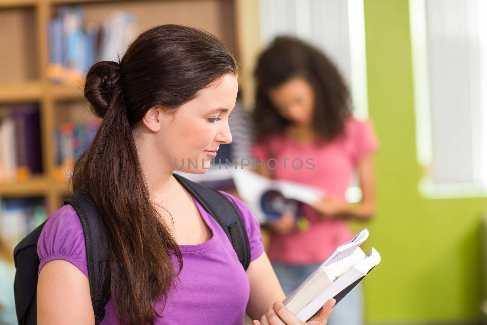 Two college students reading books in the library