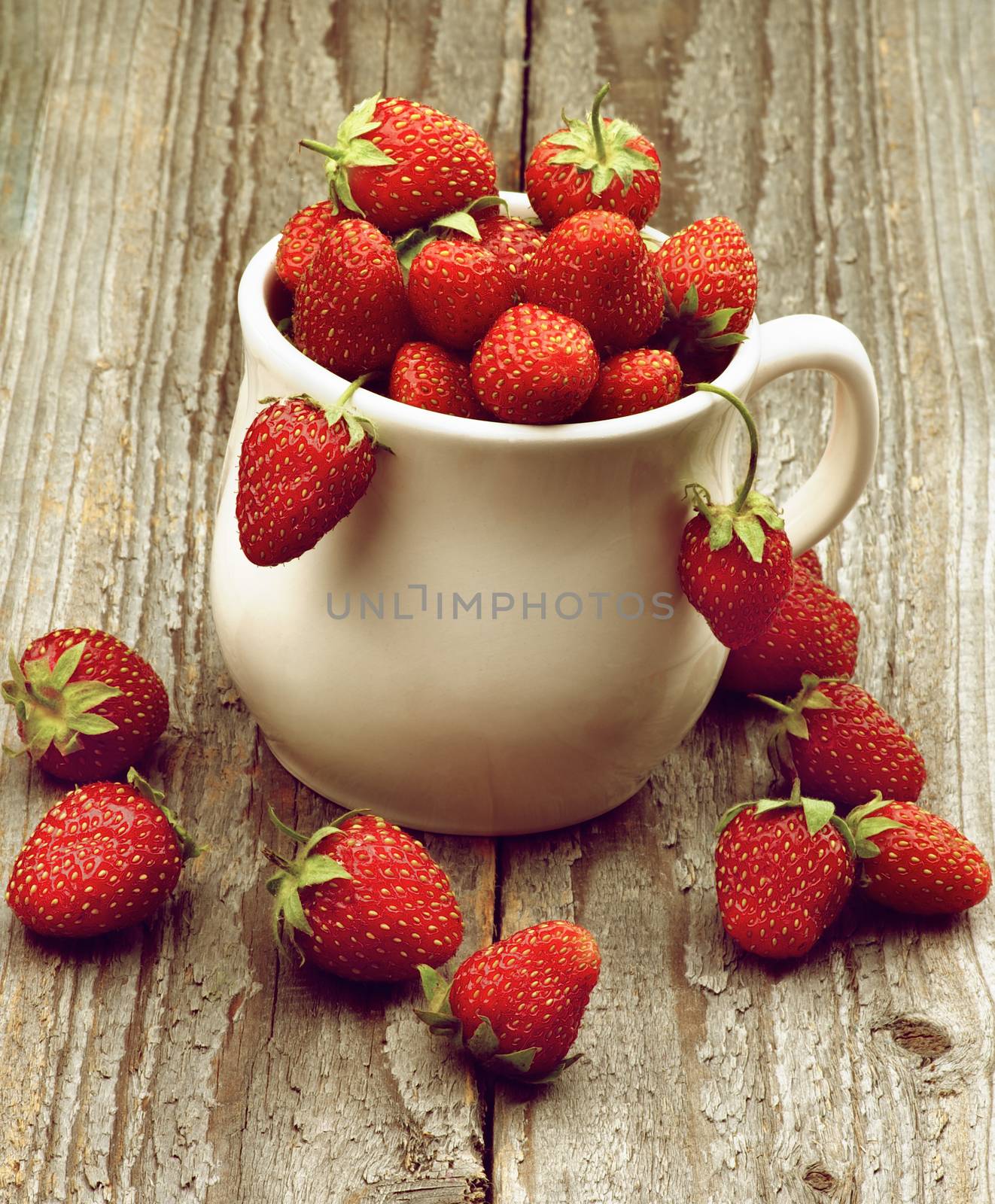 Heap of Fresh Ripe Forest Strawberries in White Bowl closeup on Rustic Wooden background. Retro Styled