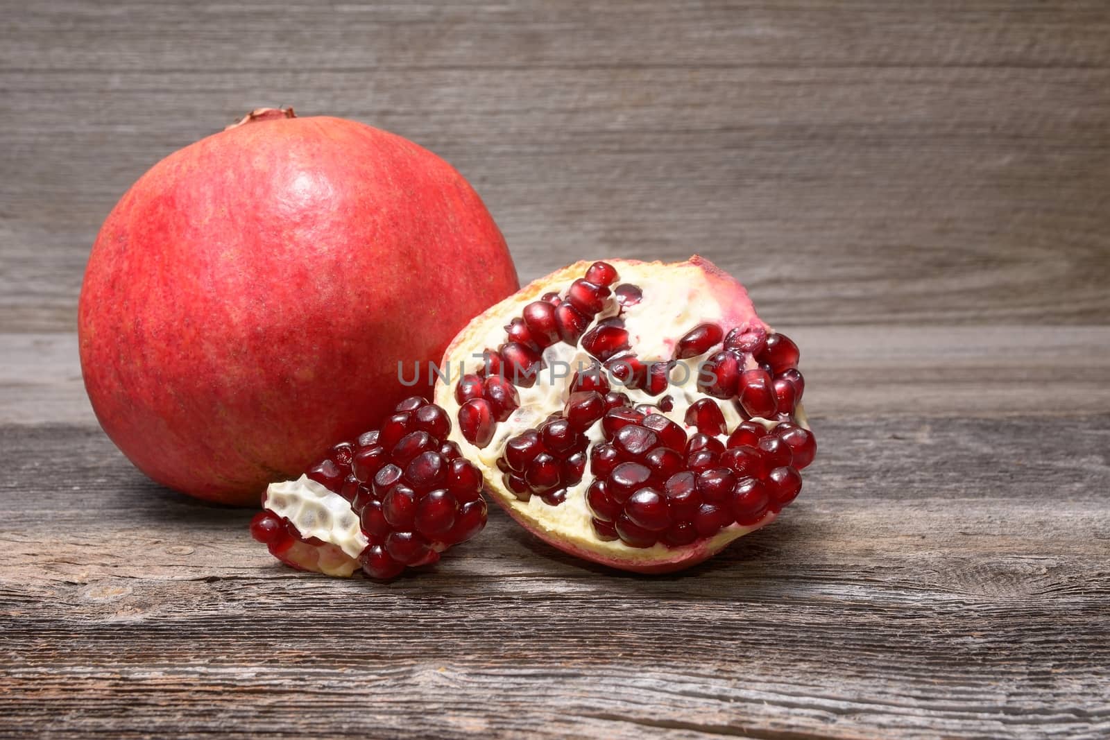 Red juicy pomegranate, on dark rustic wooden table by comet