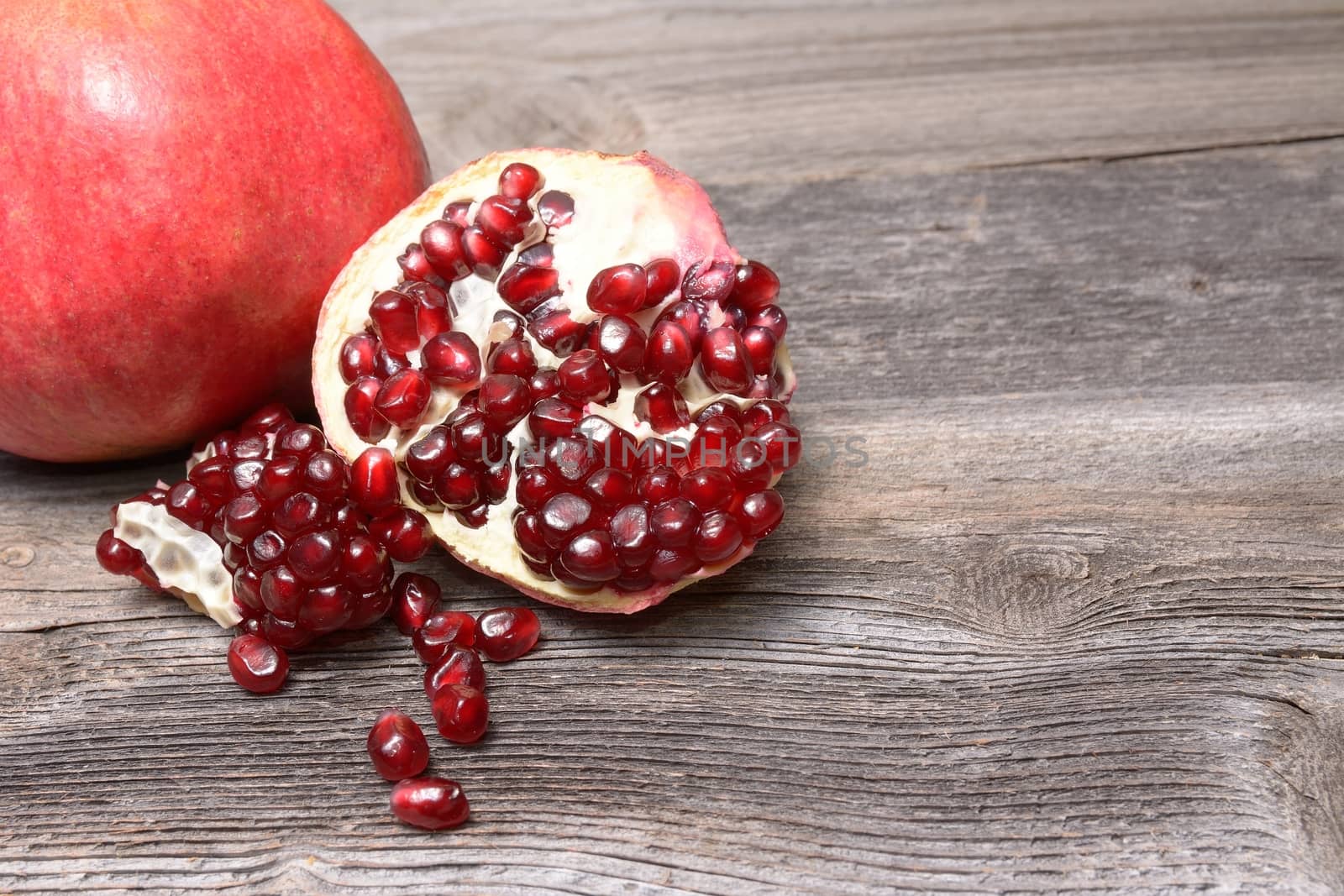 Red juicy pomegranate, on dark rustic wooden table by comet