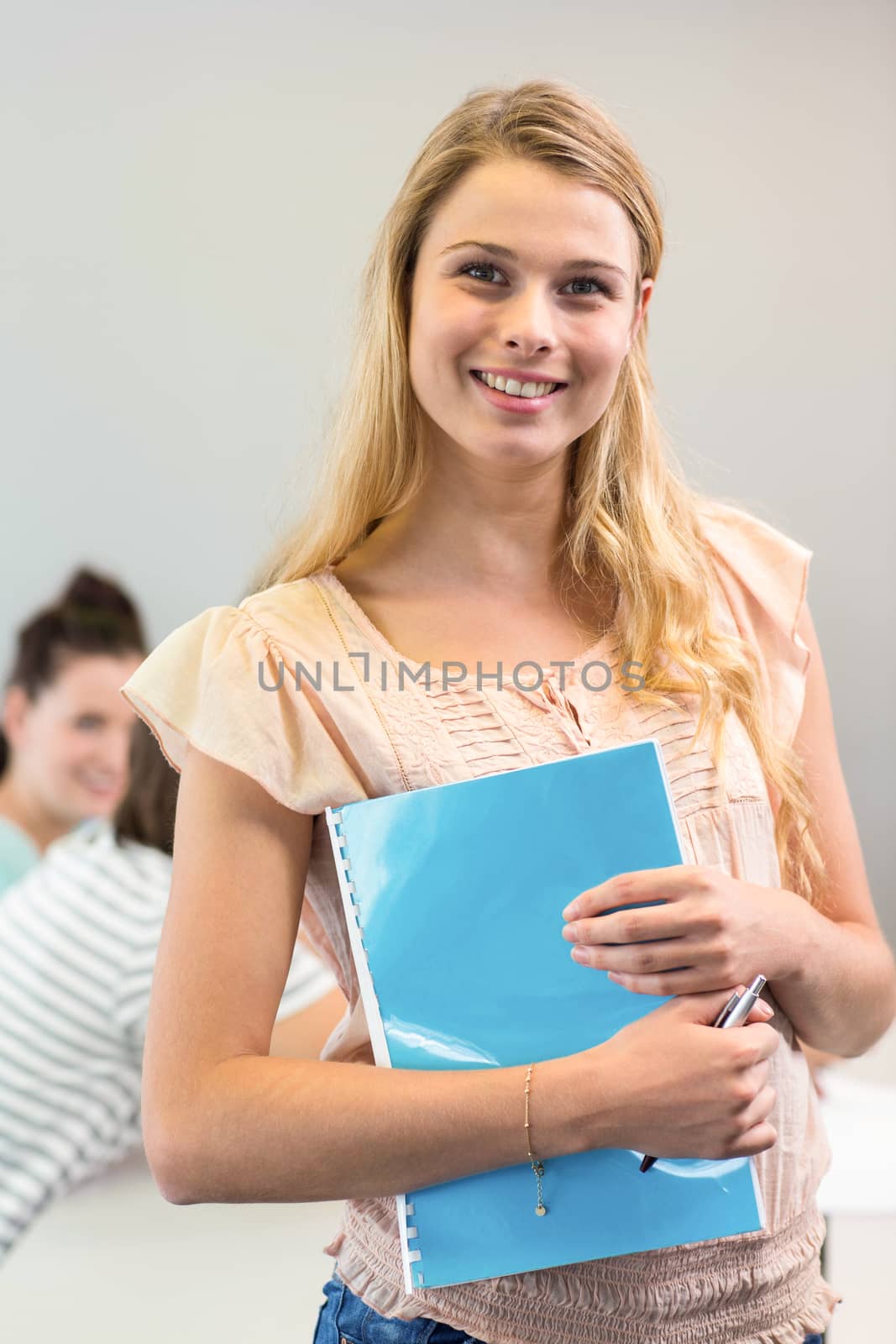 Portrait of happy female student holding folder in college