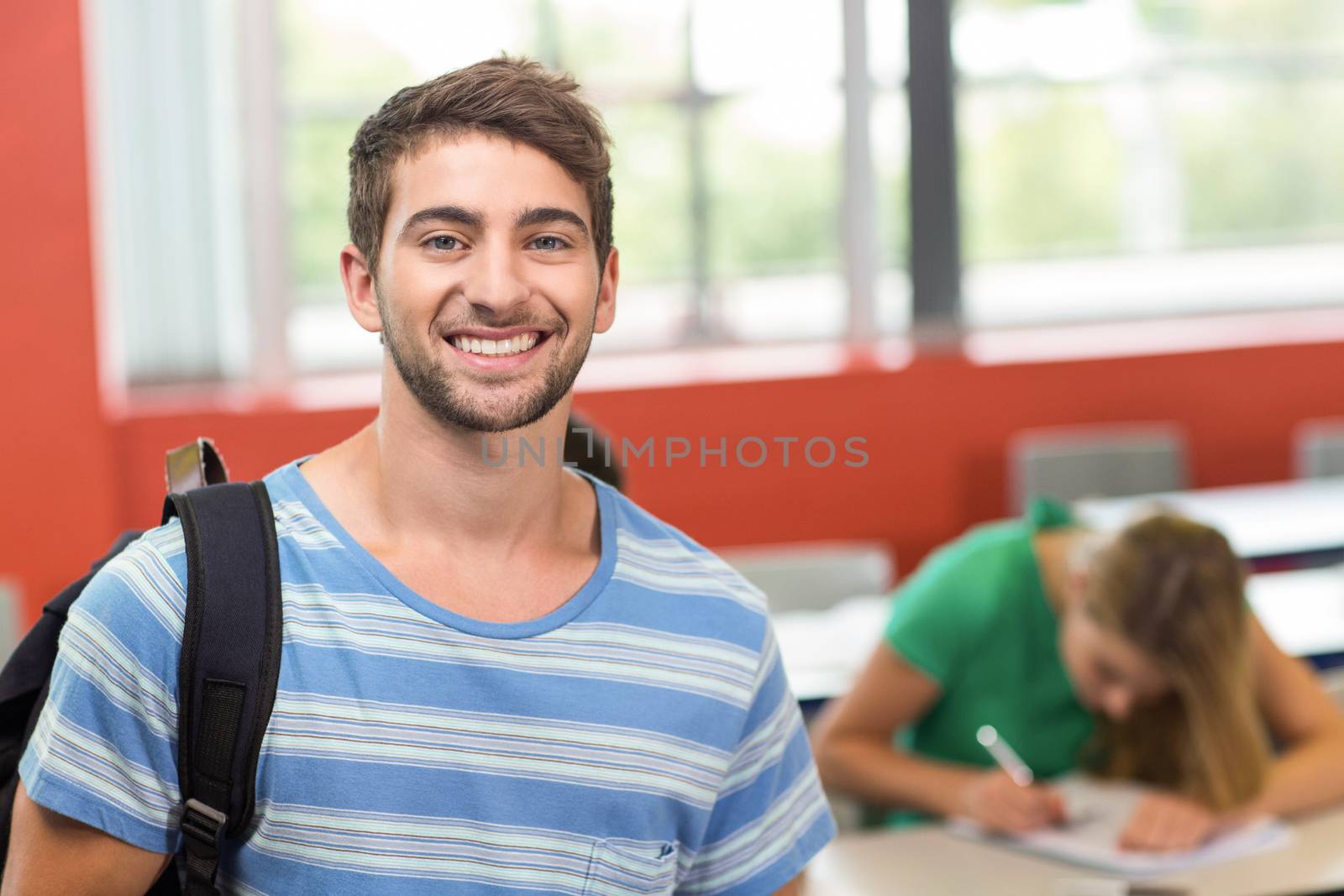 Portrait of happy male student standing in the classroom