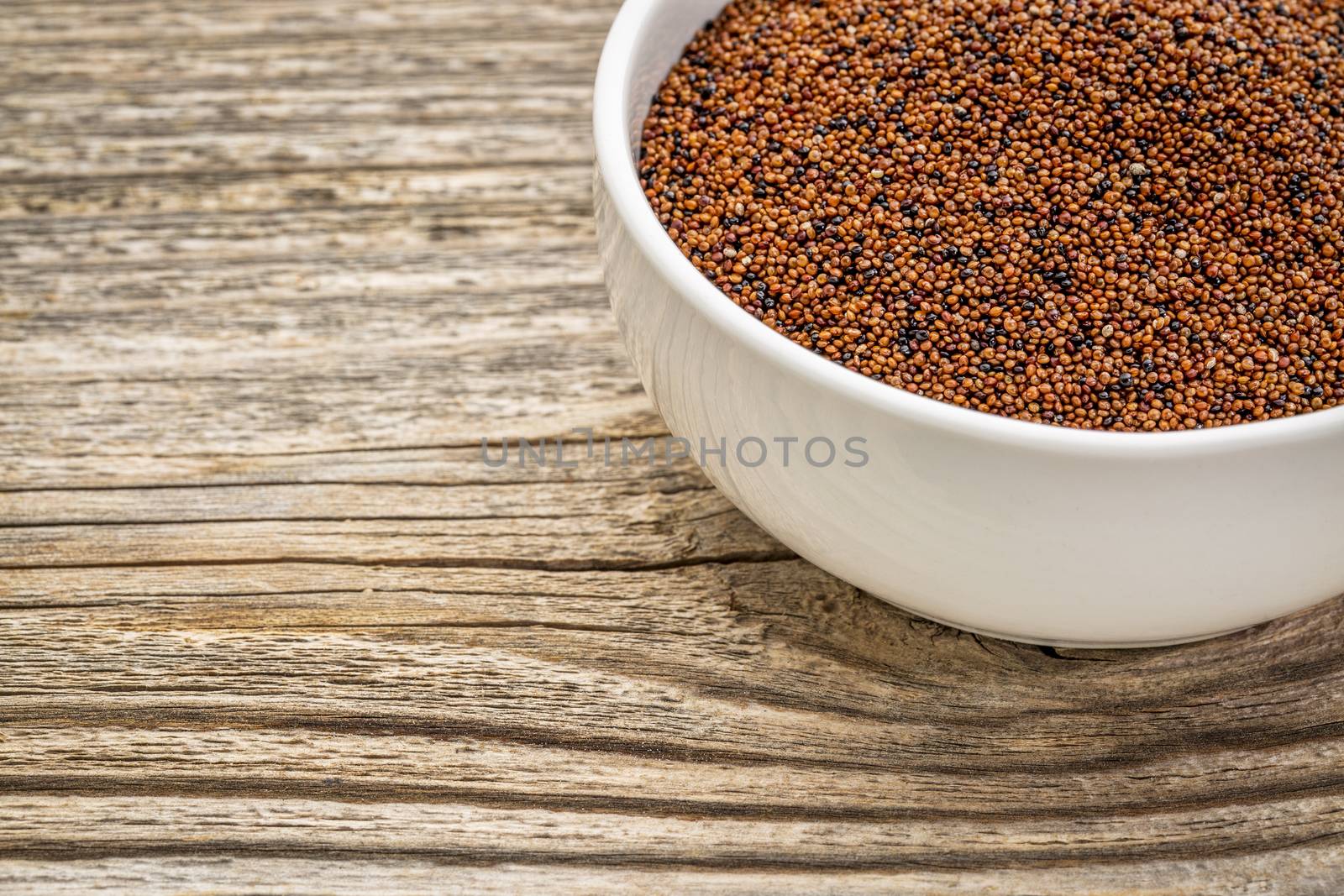 gluten free kaniwa grain (also known as baby quinoa) in a small ceramic bowl against grained wood