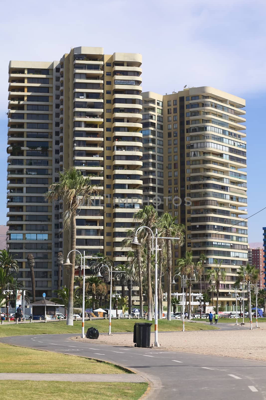 IQUIQUE, CHILE - JANUARY 23, 2015: Bike path leading between Cavancha beach and Arturo Prat Chacon avenue with a modern tall residential building along the road on January 23, 2015 in Iquique, Chile. Iquique is a popular beach town and free port city in Northern Chile. 