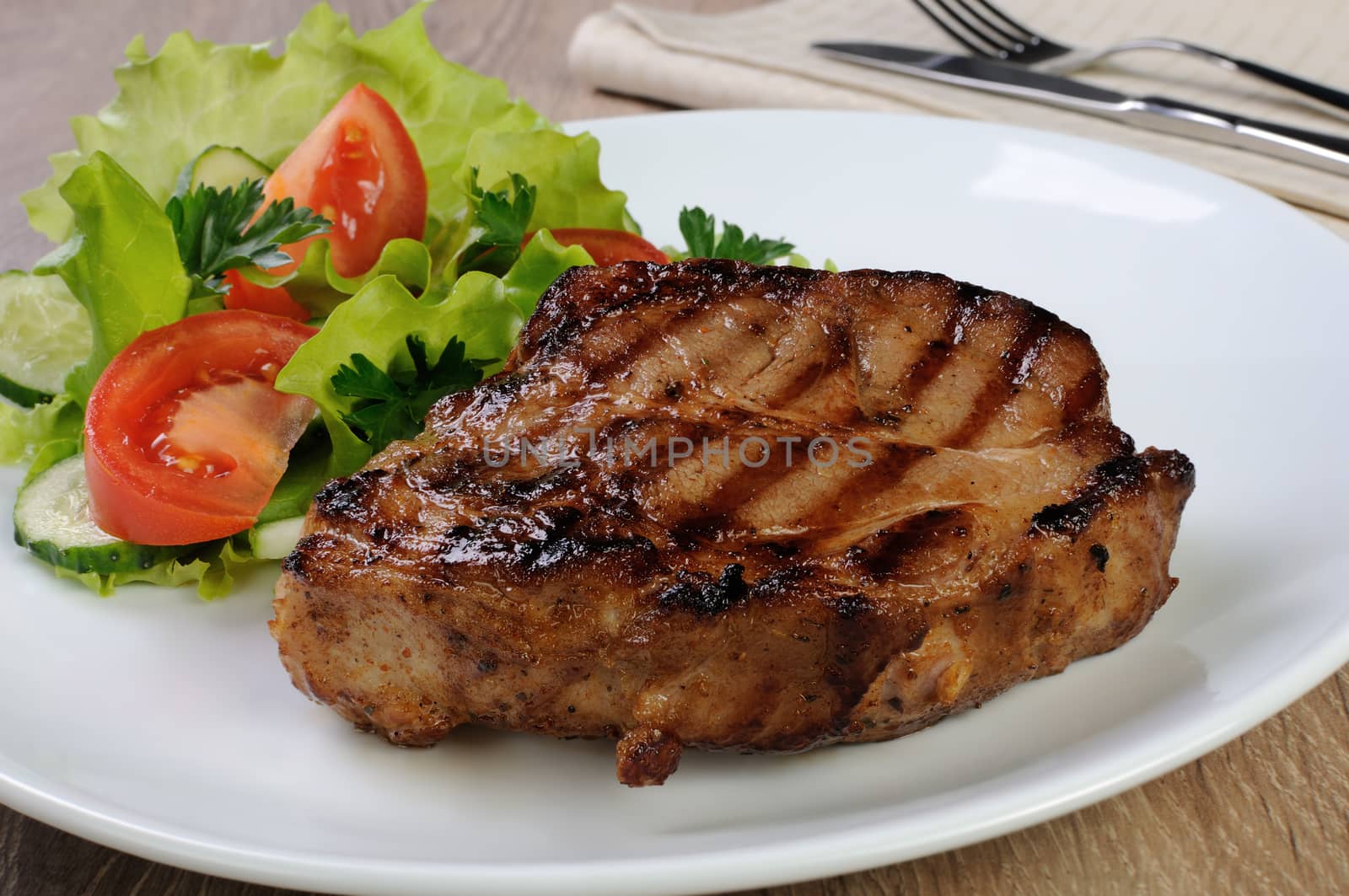 piece of juicy pork steak grilled with a salad