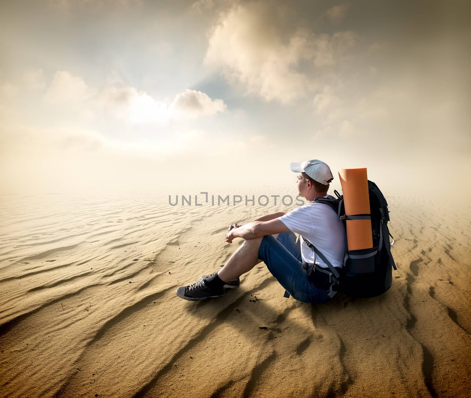 Tourist sitting in a sand desert and looking at sun