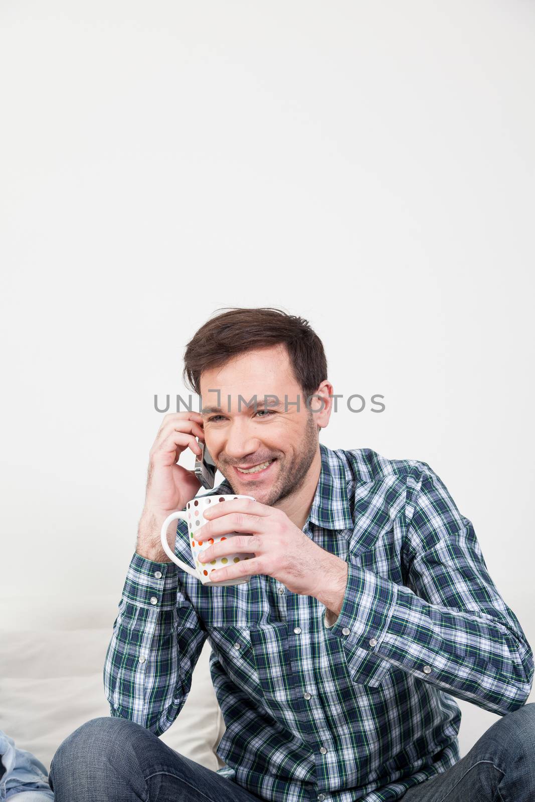 Man talking on the cellphone holding a cup of tea