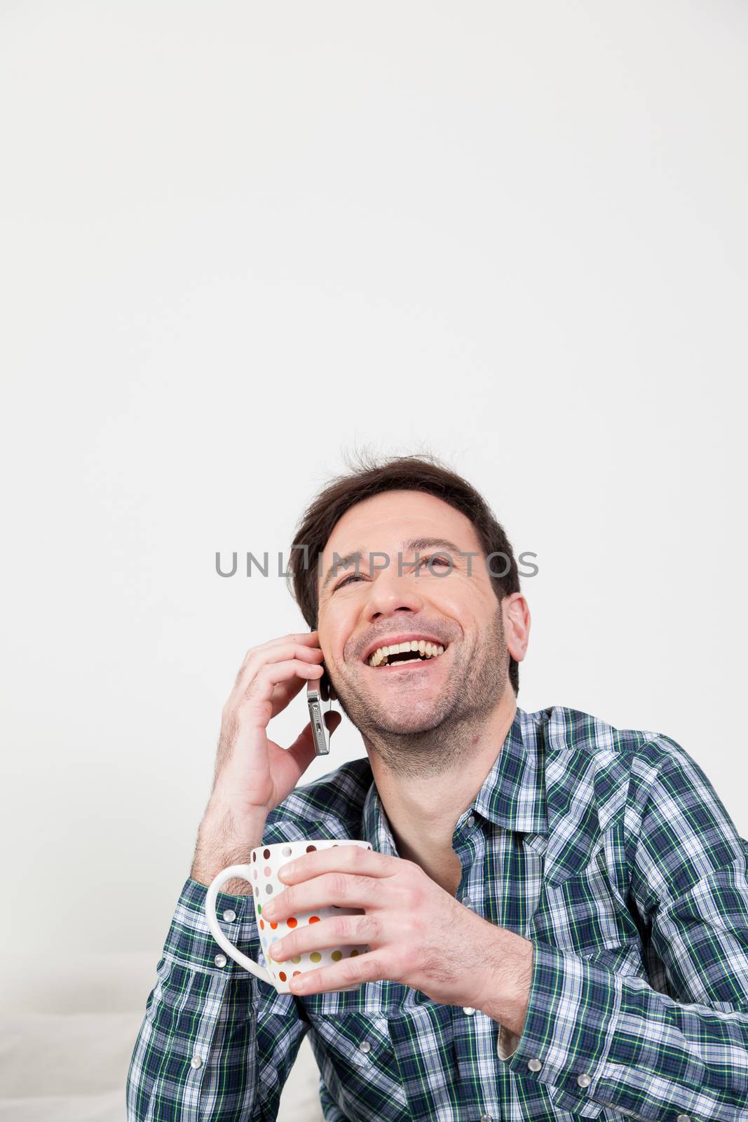 Man laughing on the cellphone with a cup of coffee