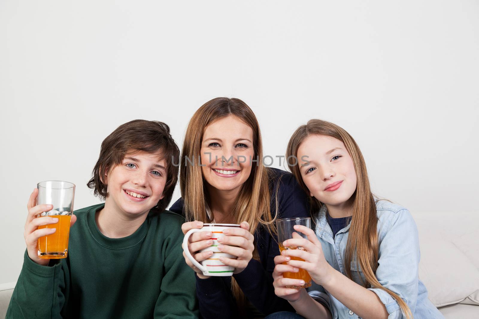Mom with your two sons drinking juice in the breakfast by ifilms