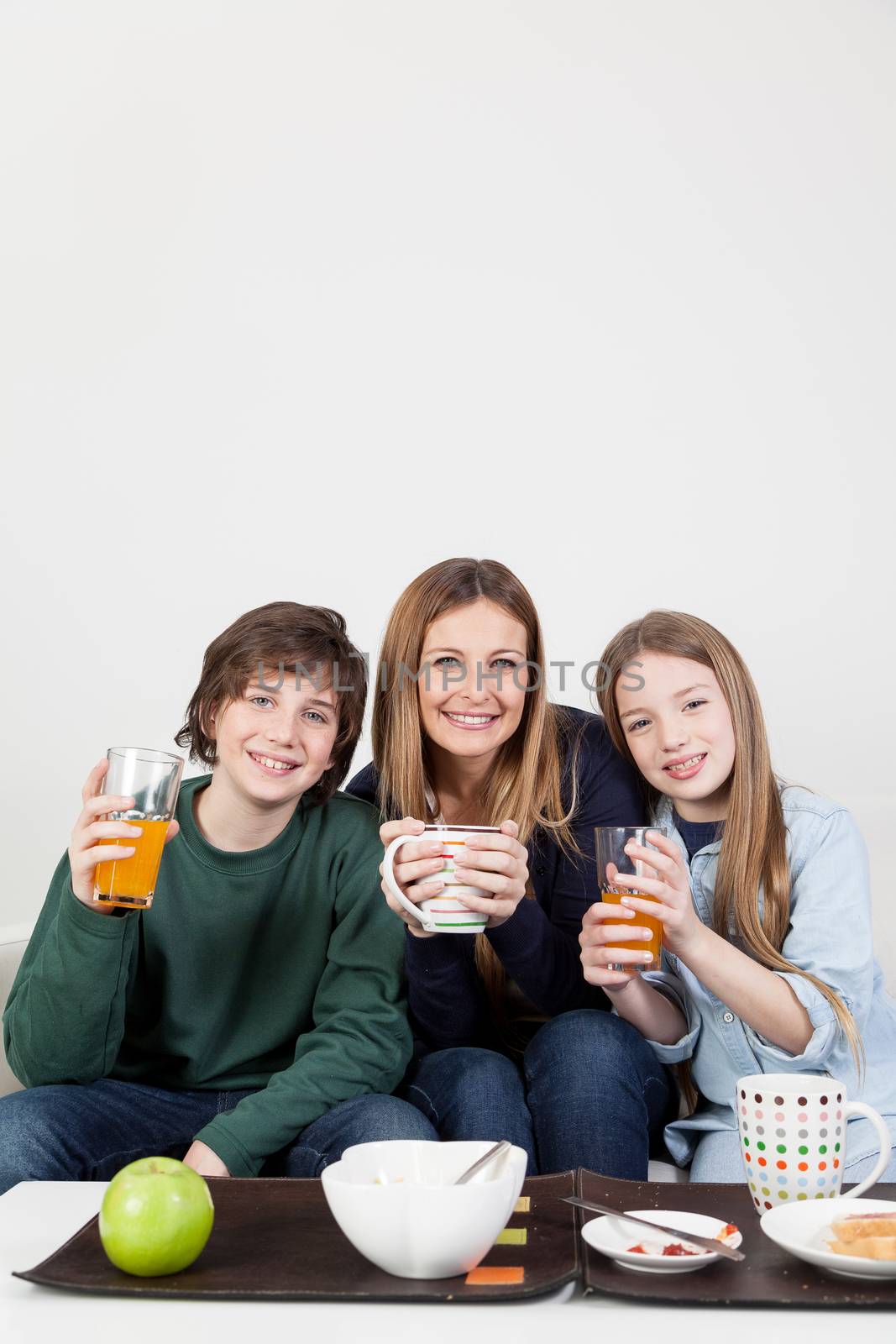 Mom with your two sons drinking juice in the breakfast