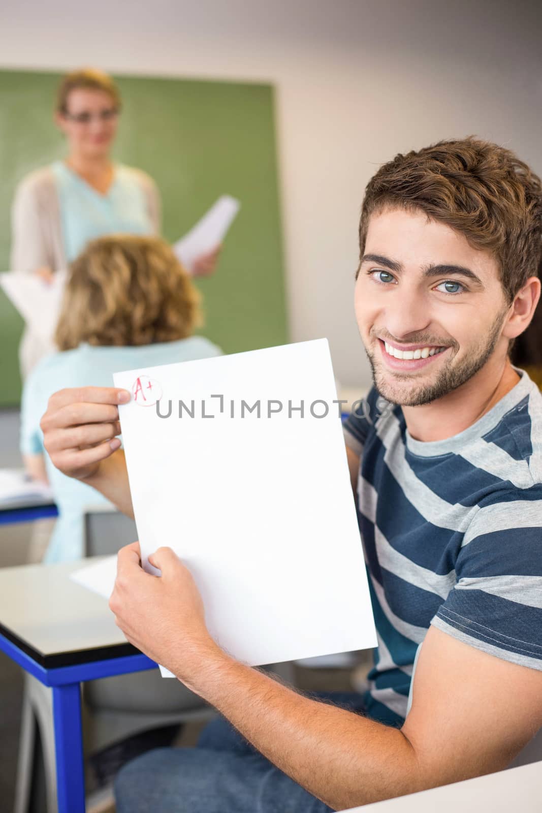 Happy male student holding paper by Wavebreakmedia