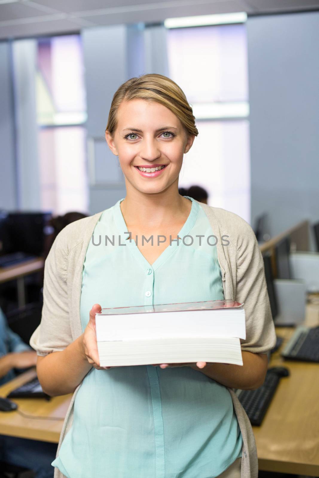 Female teacher holding books in computer class by Wavebreakmedia