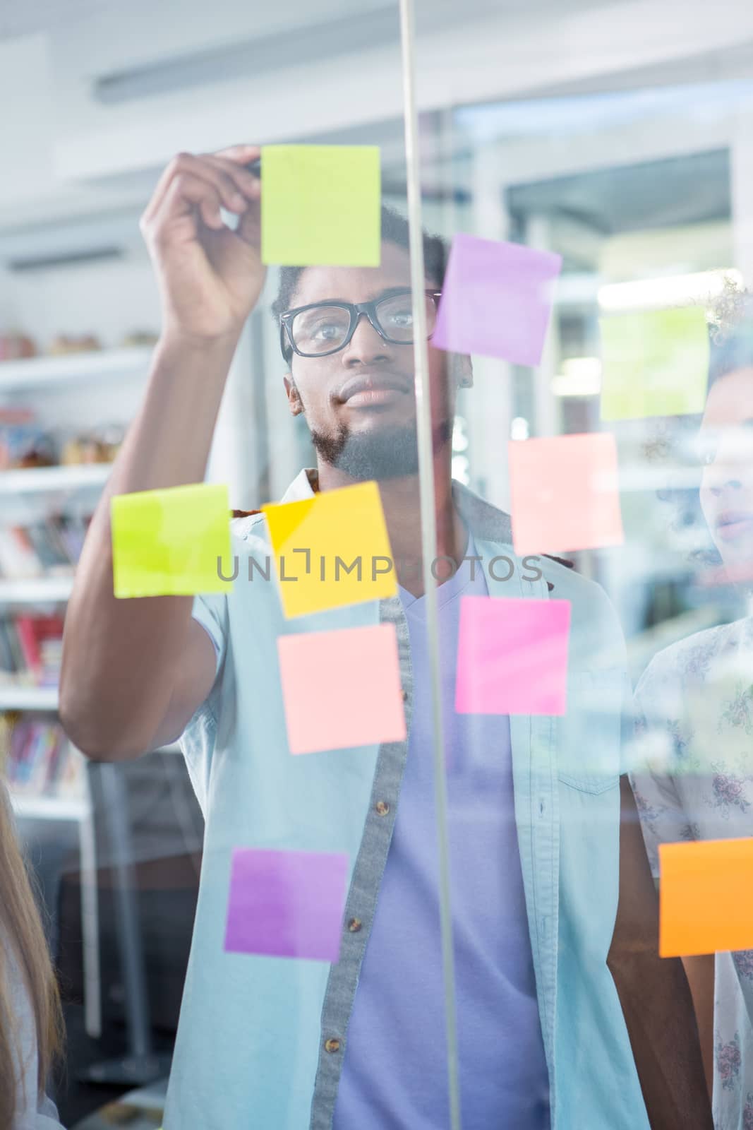 Creative young businessman writing on adhesive note in office