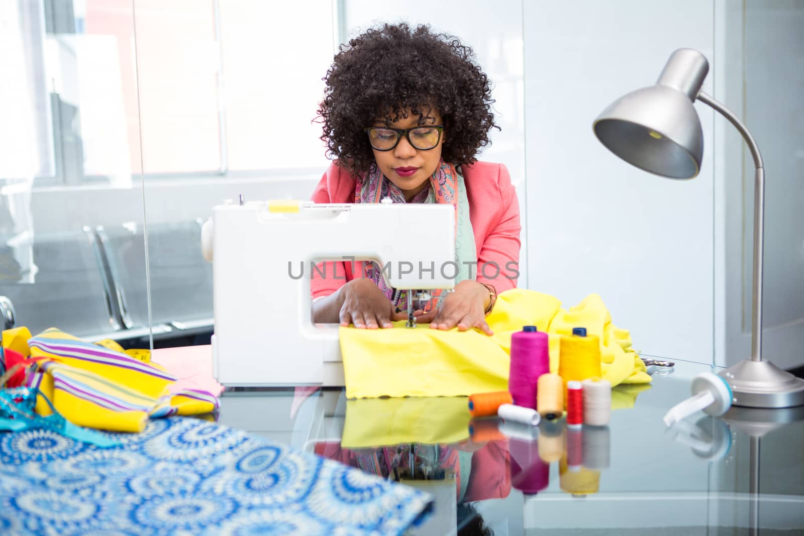 Attractive female fashion designer using sewing machine