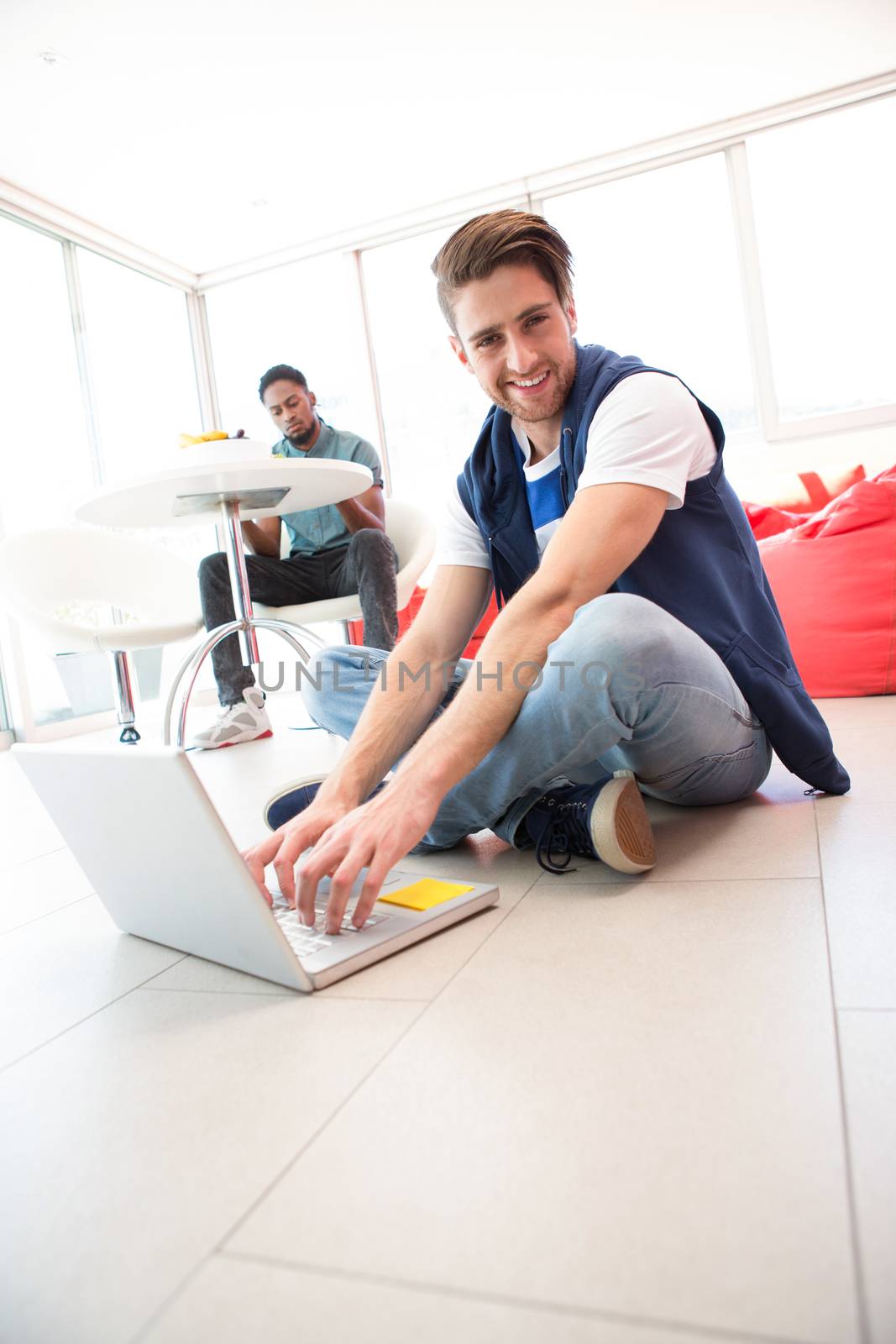 Portrait of smiling young man using laptop on floor