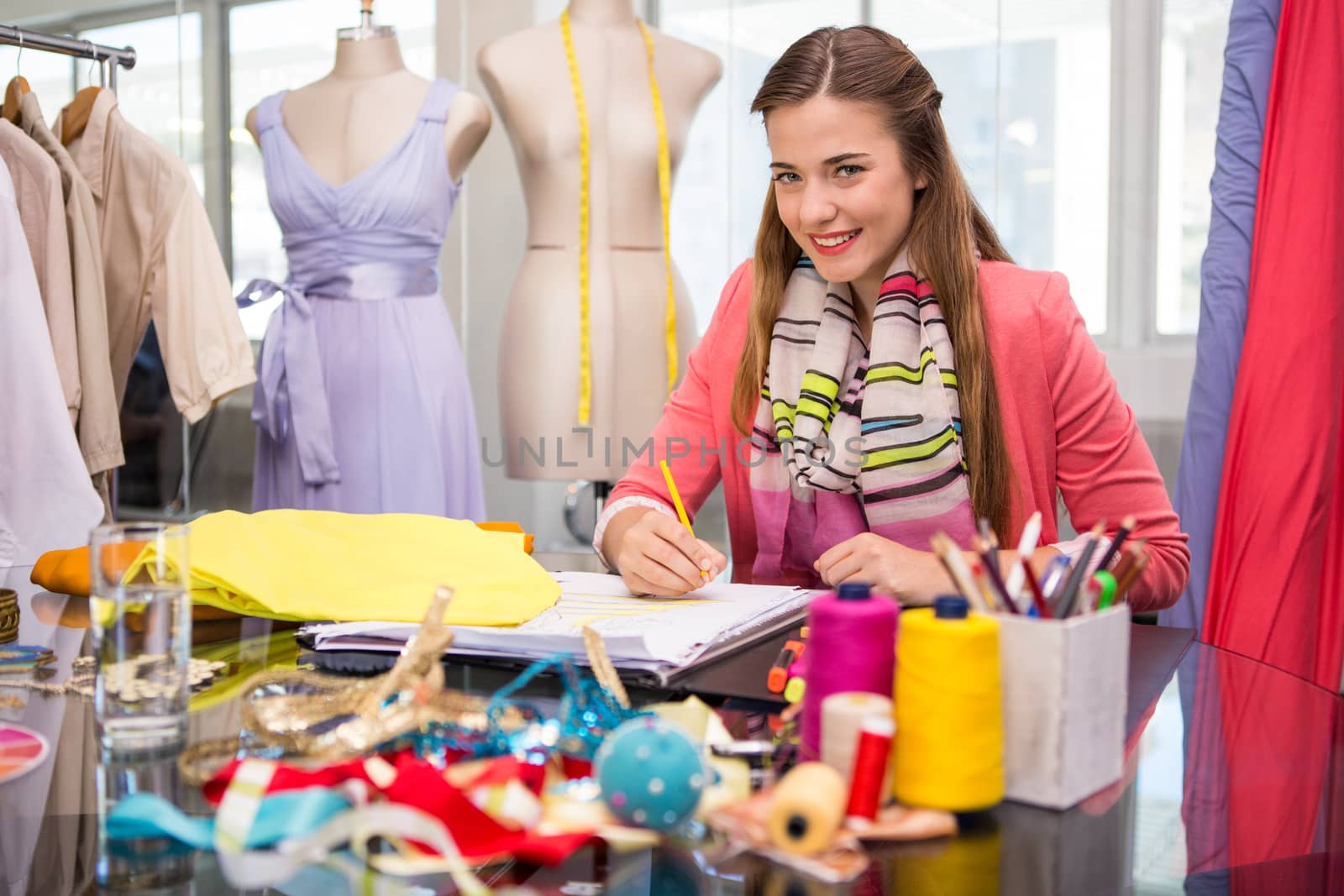 Portrait of attractive female fashion designer sketching at table