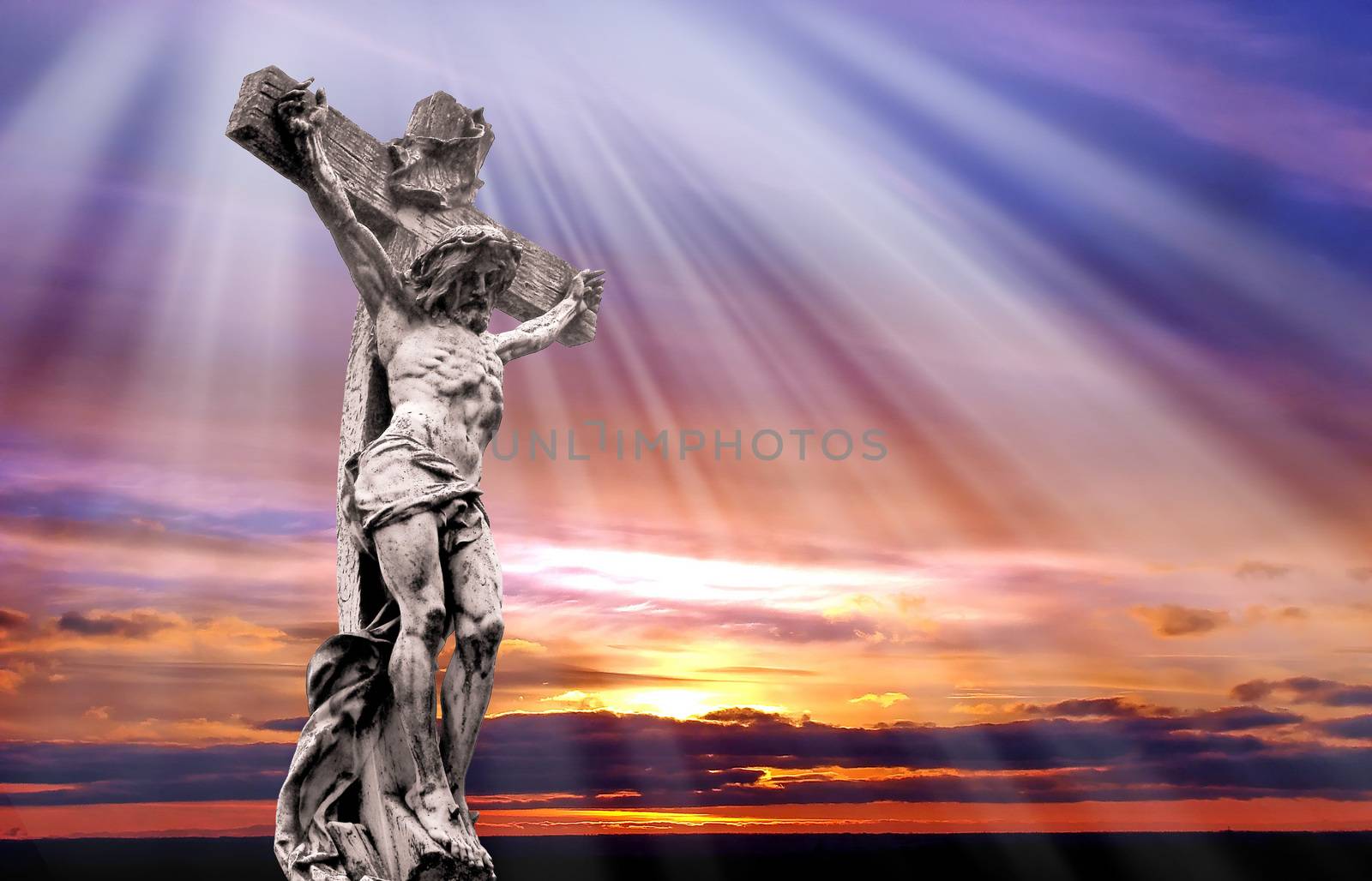 Dramatic sunset with statue of crucified Jesus Christ