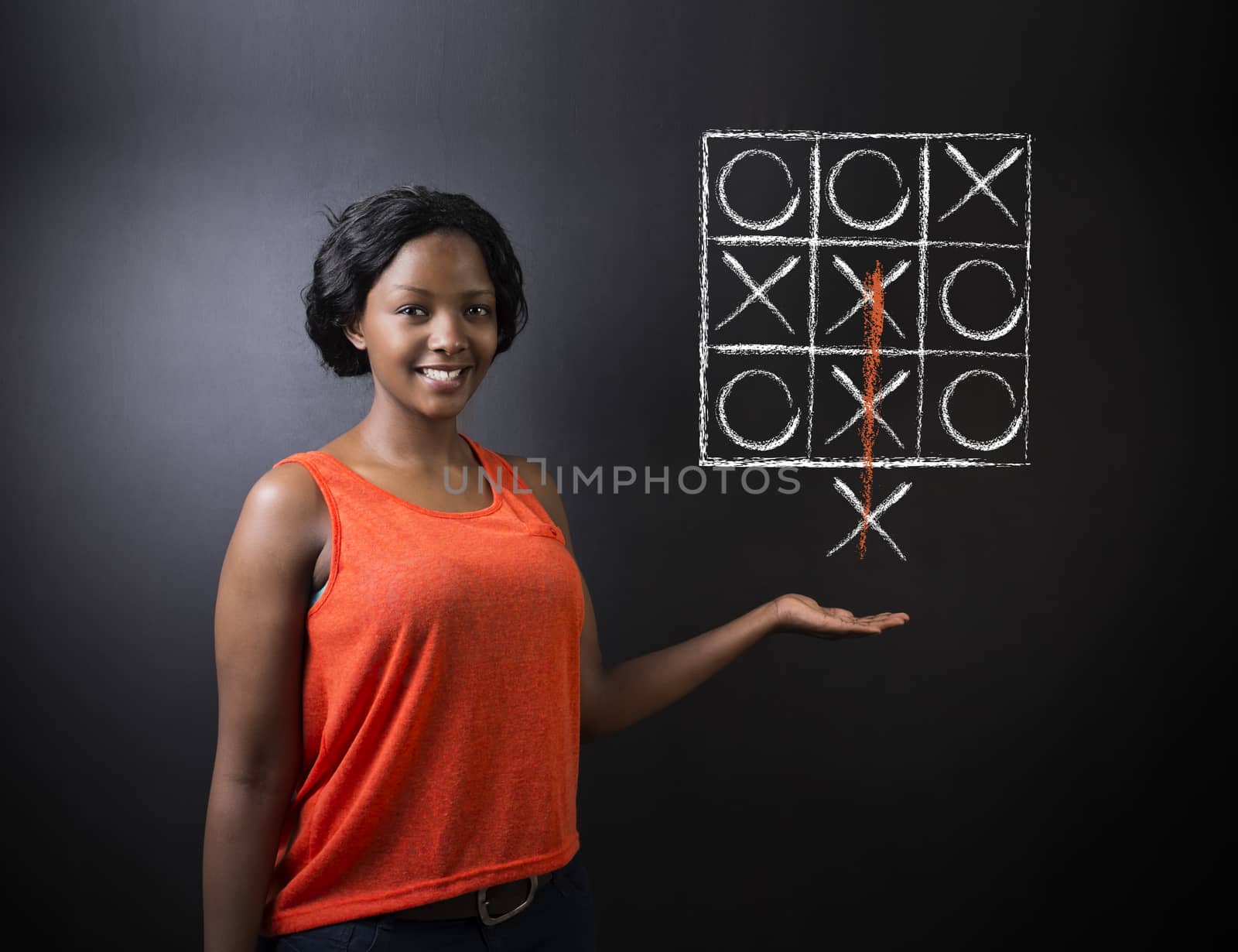 Thinking out of the box South African or African American woman teacher or student tic tac toe on blackboard background