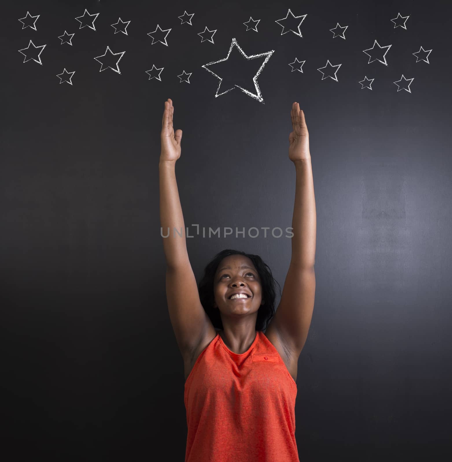 South African or African American woman teacher or student reaching for the stars success against blackboard background