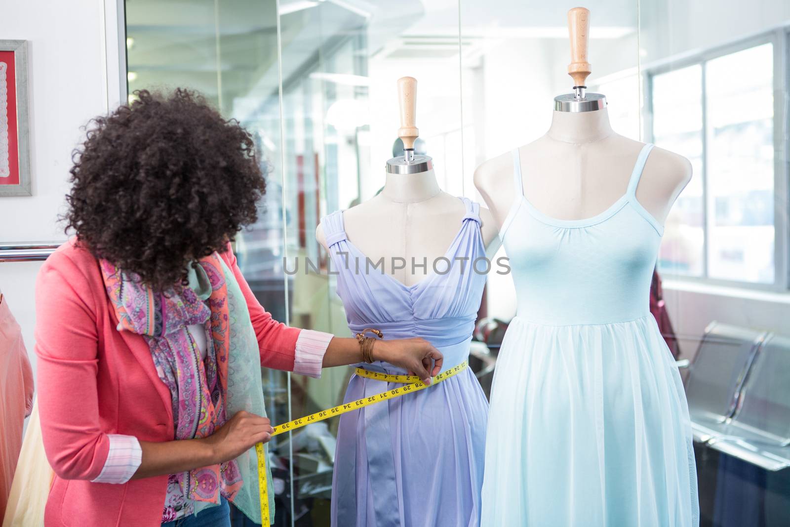 Female fashion designer measuring dummy waist