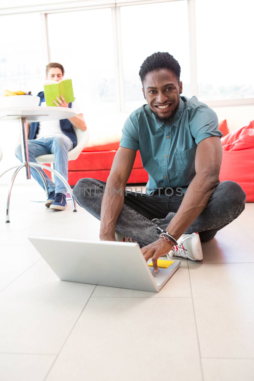 Portrait of smiling young man using laptop on floor