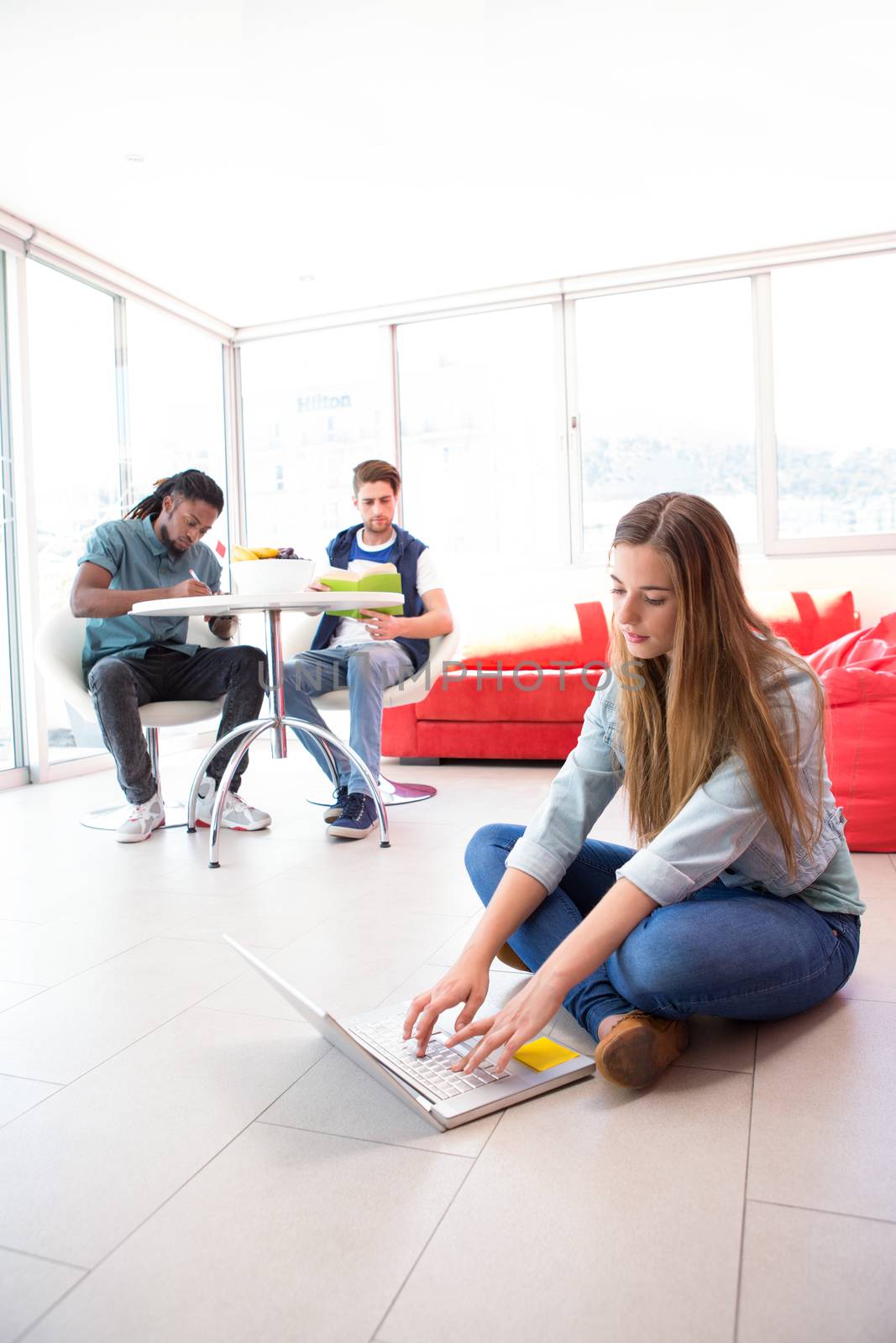 Casual young woman using laptop on floor by Wavebreakmedia