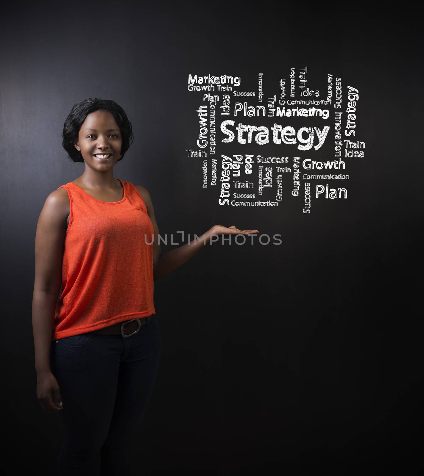 South African or African American woman teacher or student with her hand out standing against a blackboard background with a chalk strategy diagram