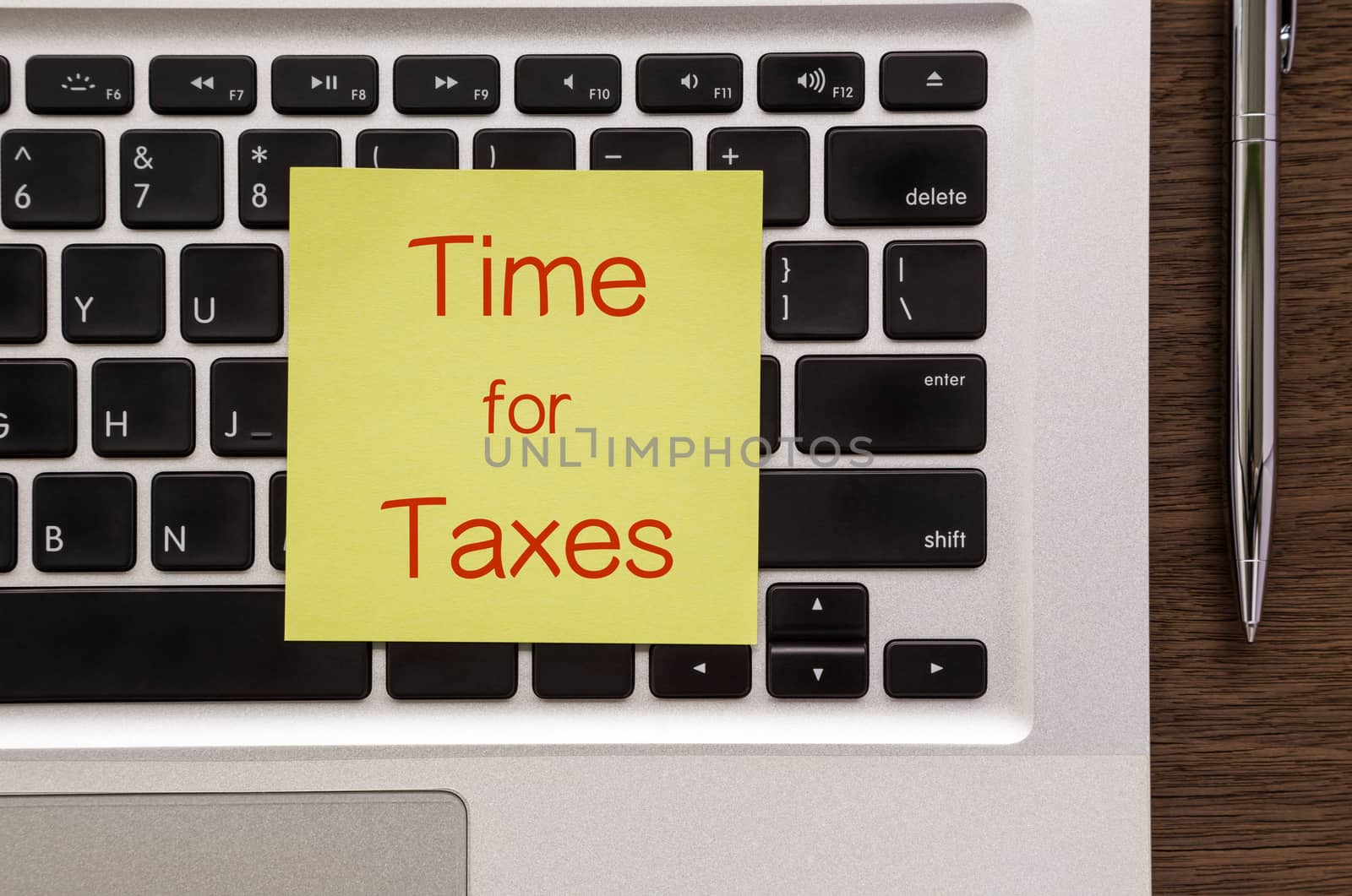 Notepad with words " Time for Taxes " putting on laptop  by vinnstock