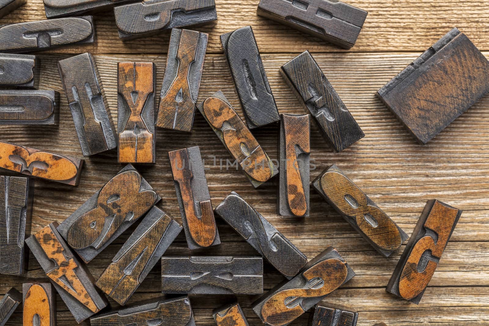 vintage letterpress wood type printing blocks stained by inks placed randomly on a wooden table