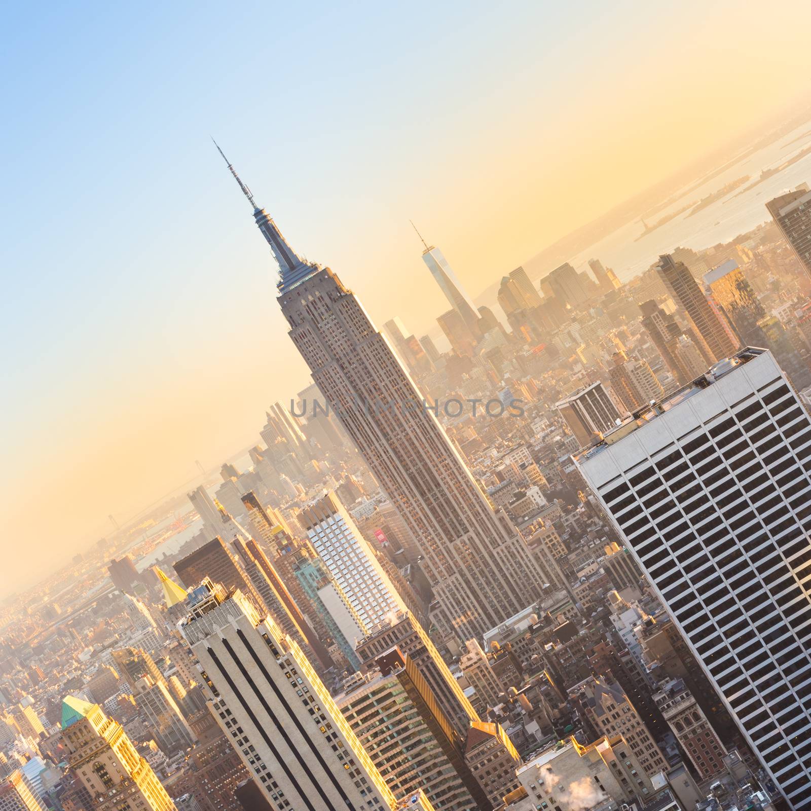 New York City. Manhattan downtown skyline with illuminated Empire State Building and skyscrapers at sunset seen from Top of the Rock observation deck. Vertical composition.