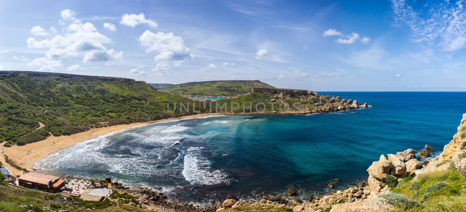 the rugged coastline of the island of Gozo are reflected in a blue sea