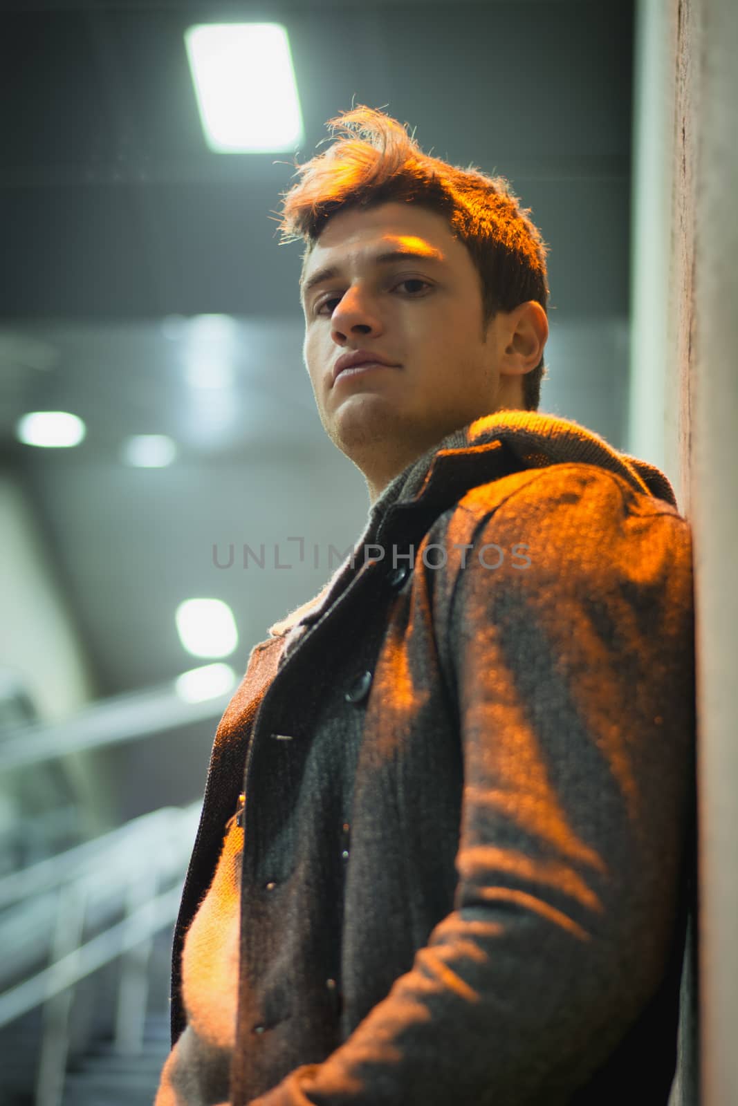 Profile shot of handsome young man inside train station looking at camera
