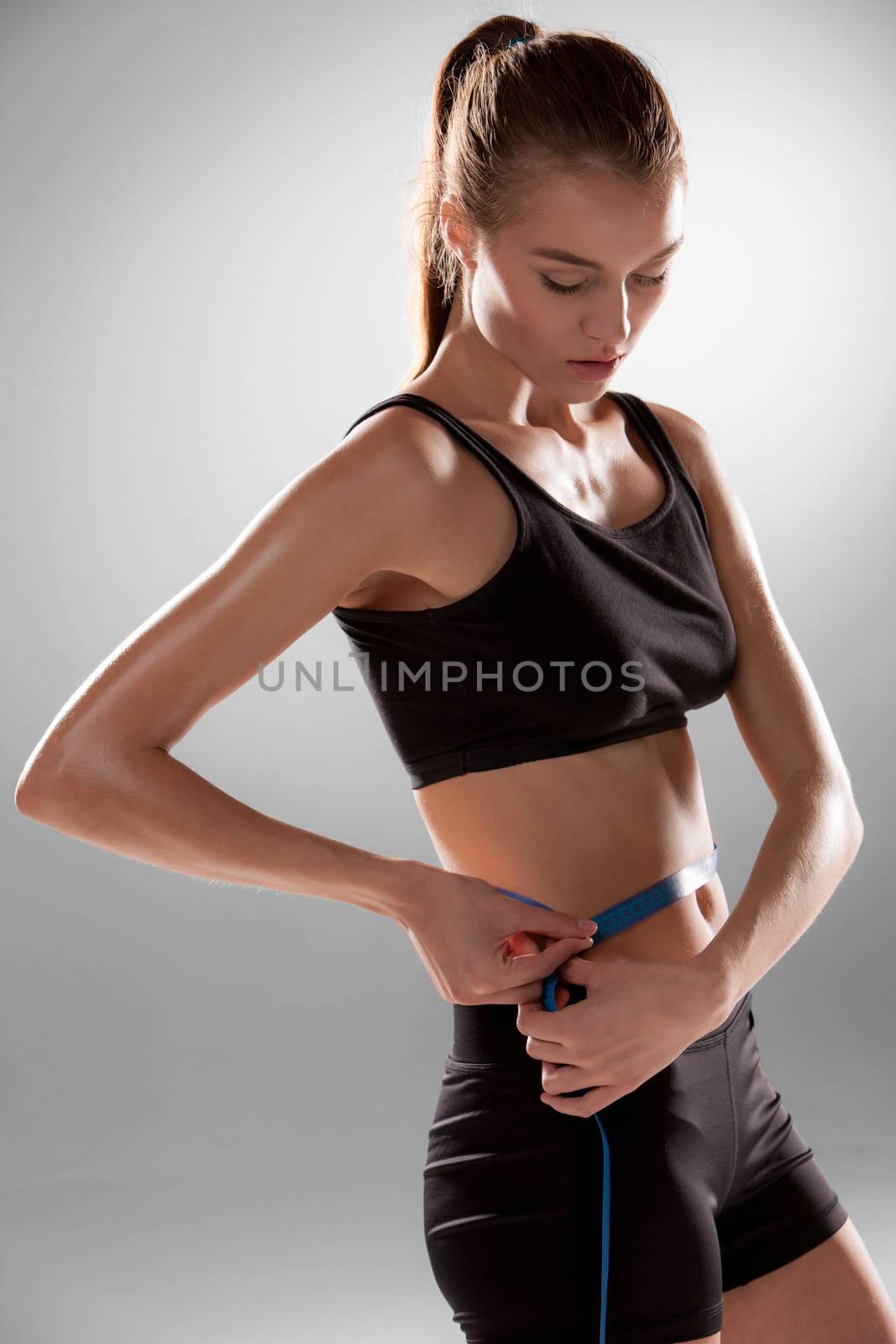 Fit and healthy waist measured with a tape isolated on gray