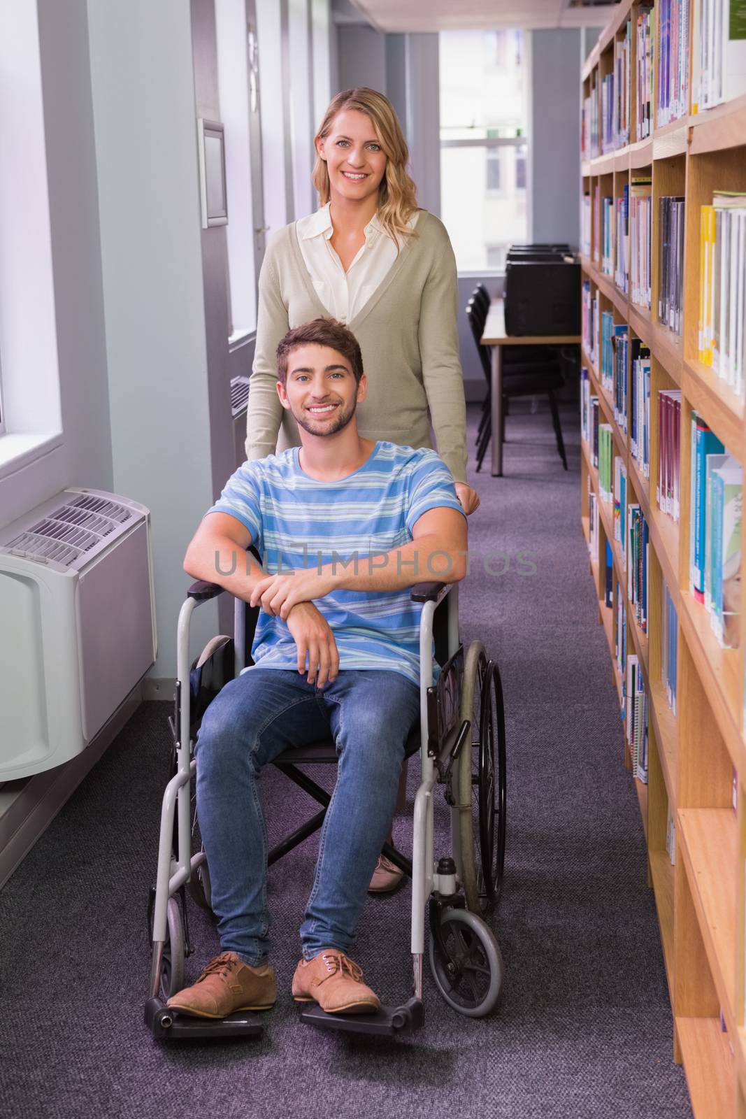 Smiling disabled student with classmate in library at the university
