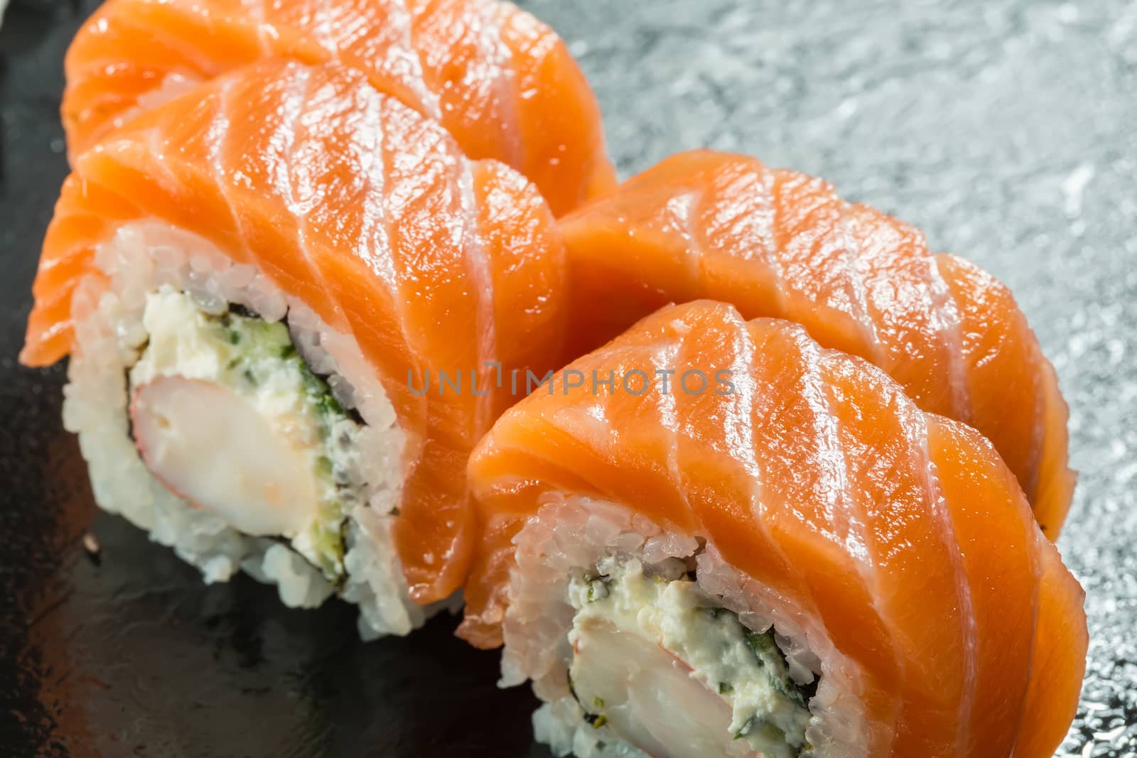 Salmon and caviar rolls served on a black plate