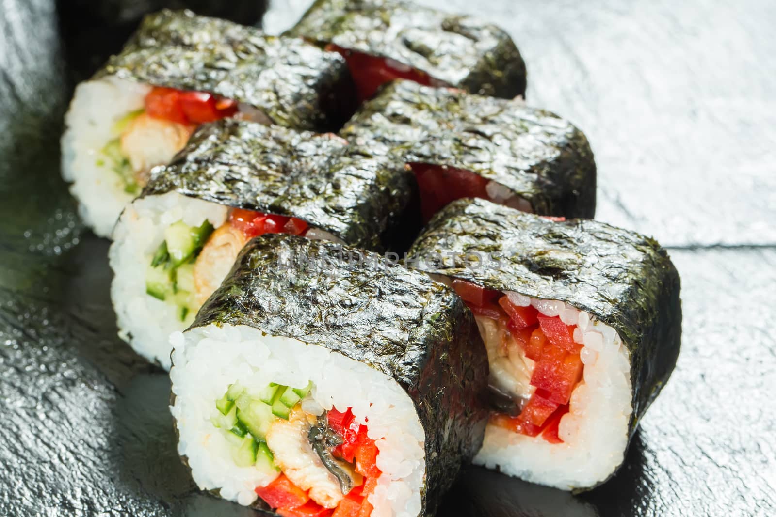 Salmon and caviar rolls served on a black plate