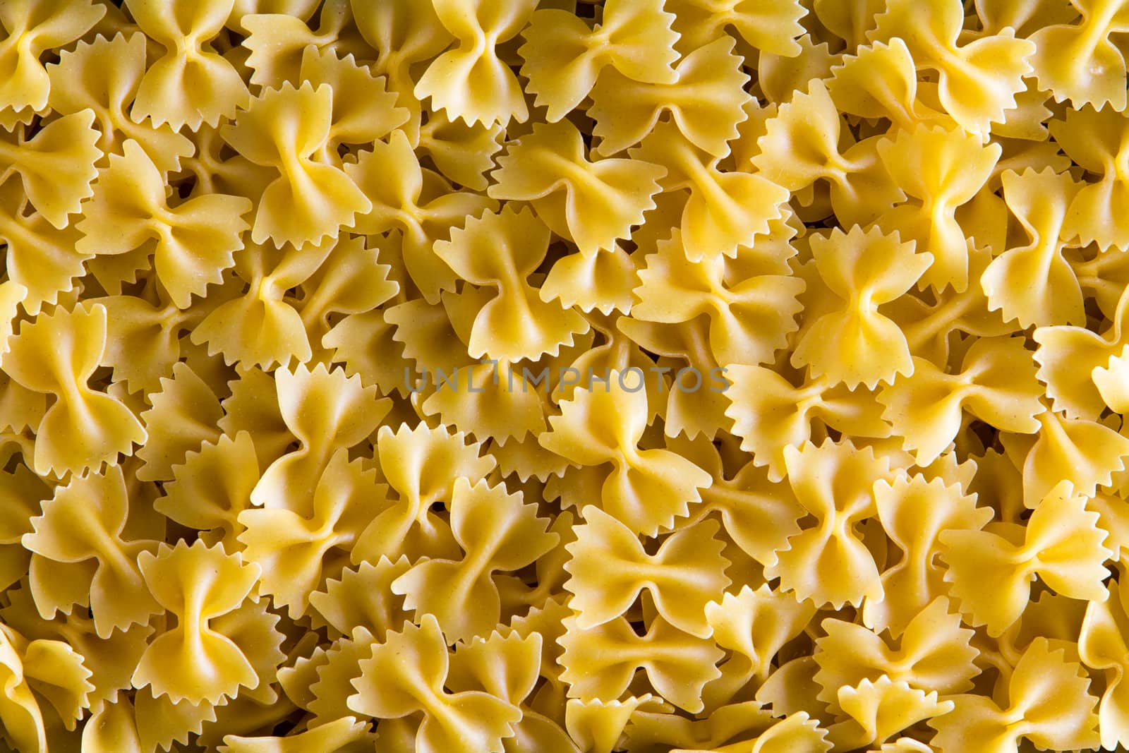 Full frame background of decorative dried Italian bow tie pasta resembling butterflies in flight in a close up overhead view